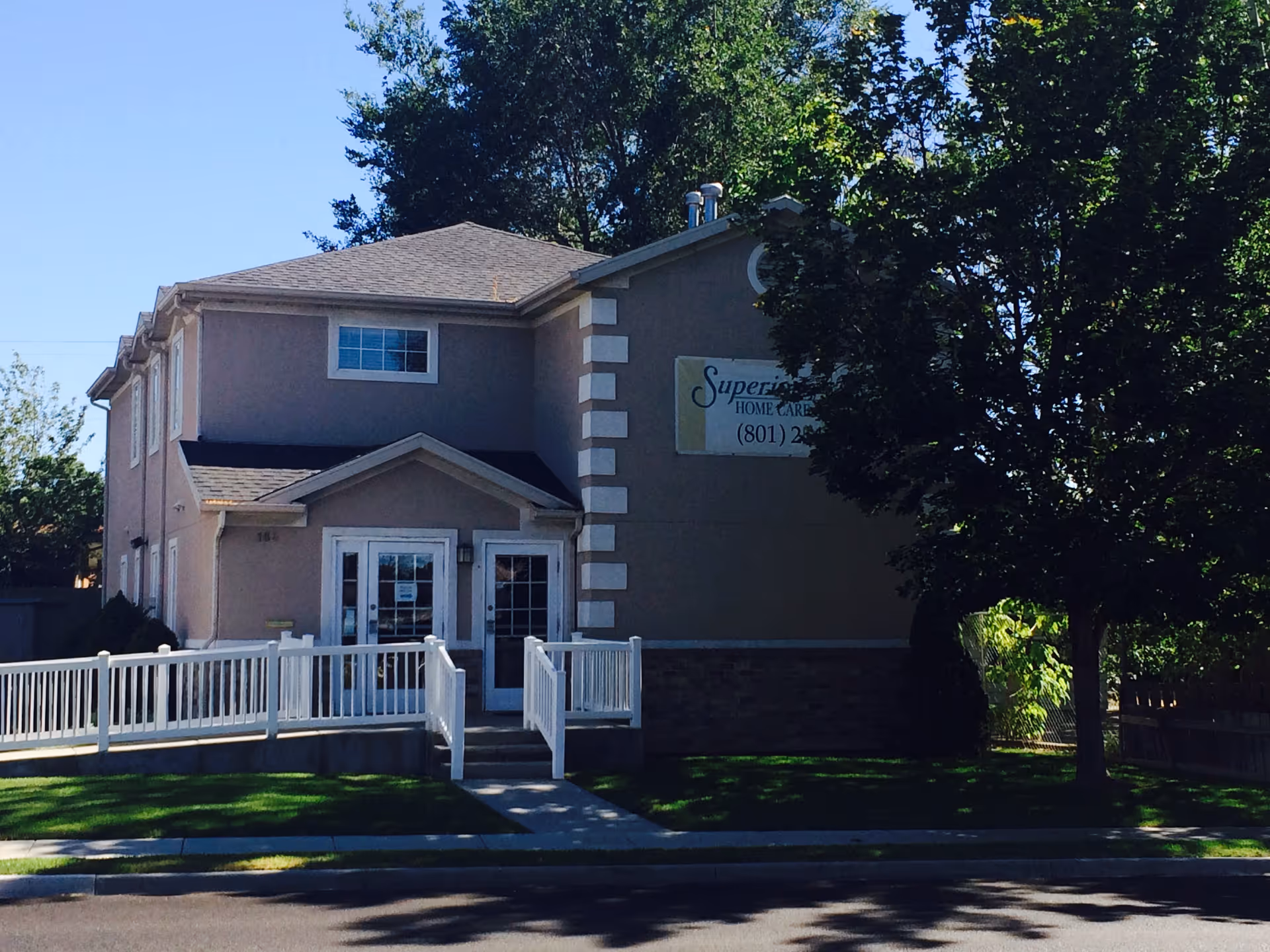 Exterior view of a beige building with white railing and a sign for Superior Home Care.