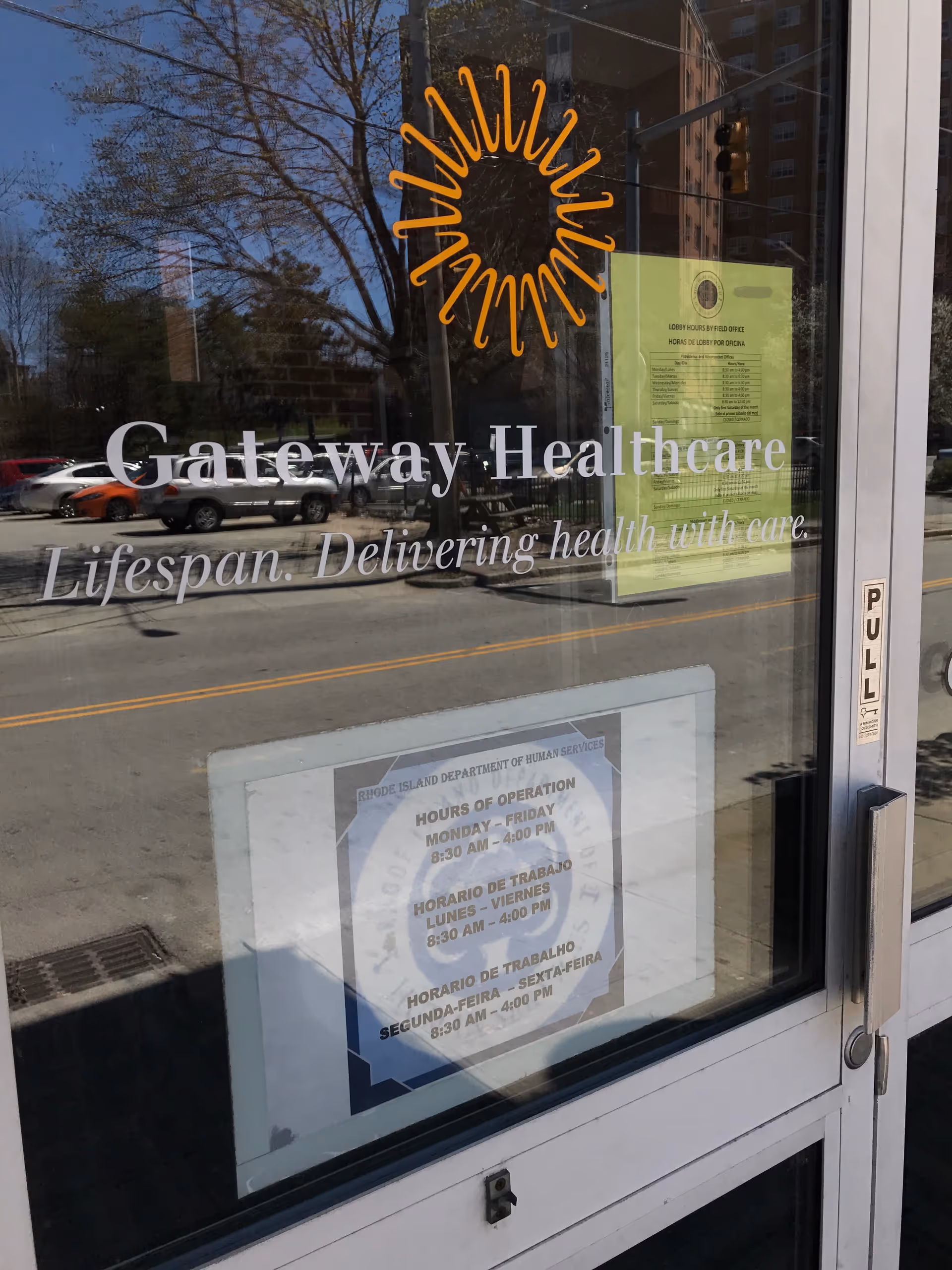 Glass storefront door showing Gateway Healthcare logo and slogan with posted hours and street reflection.