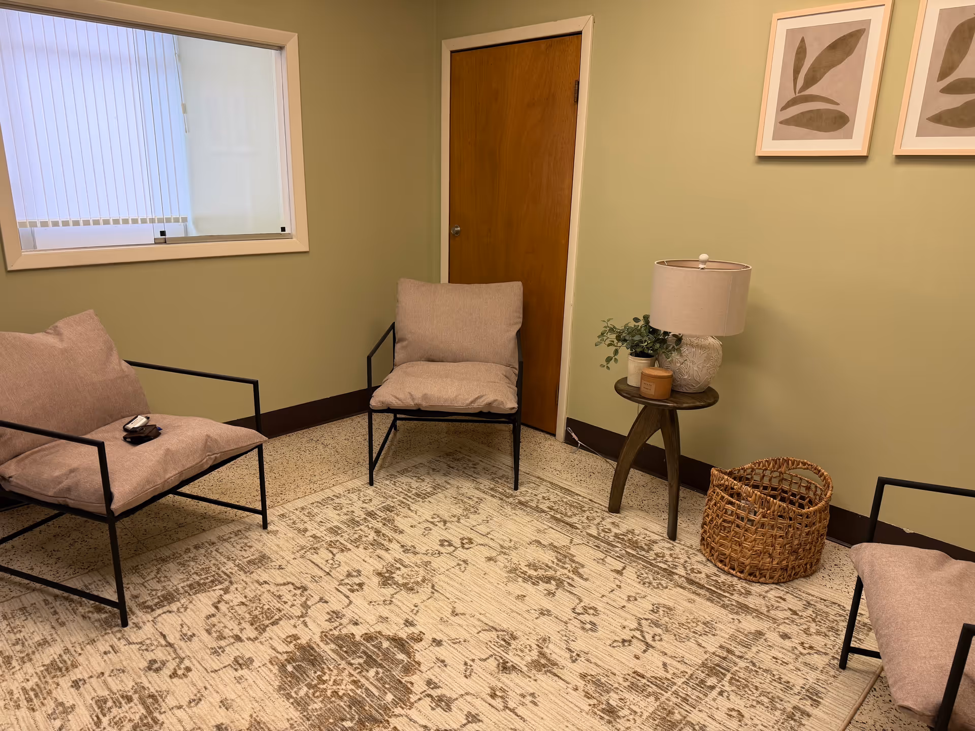 Cozy lounge with beige chairs, a side table, plant, and woven basket.