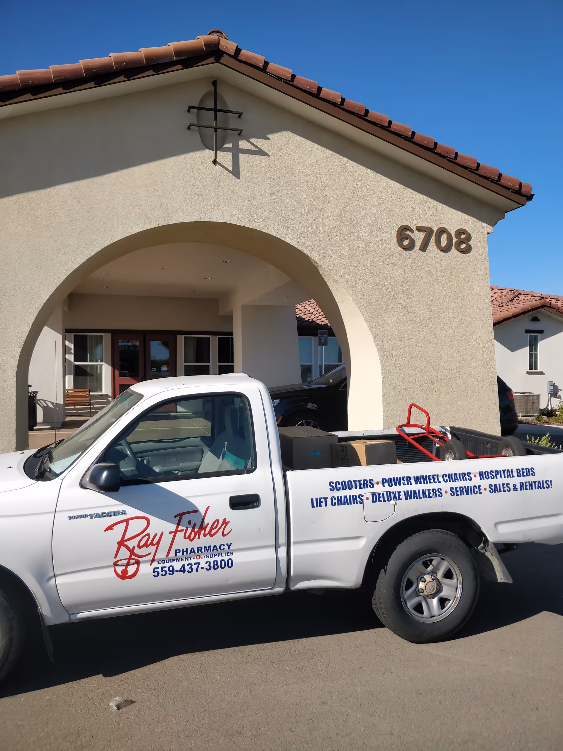 Exterior view of a beige building with a covered entrance and a white delivery truck.