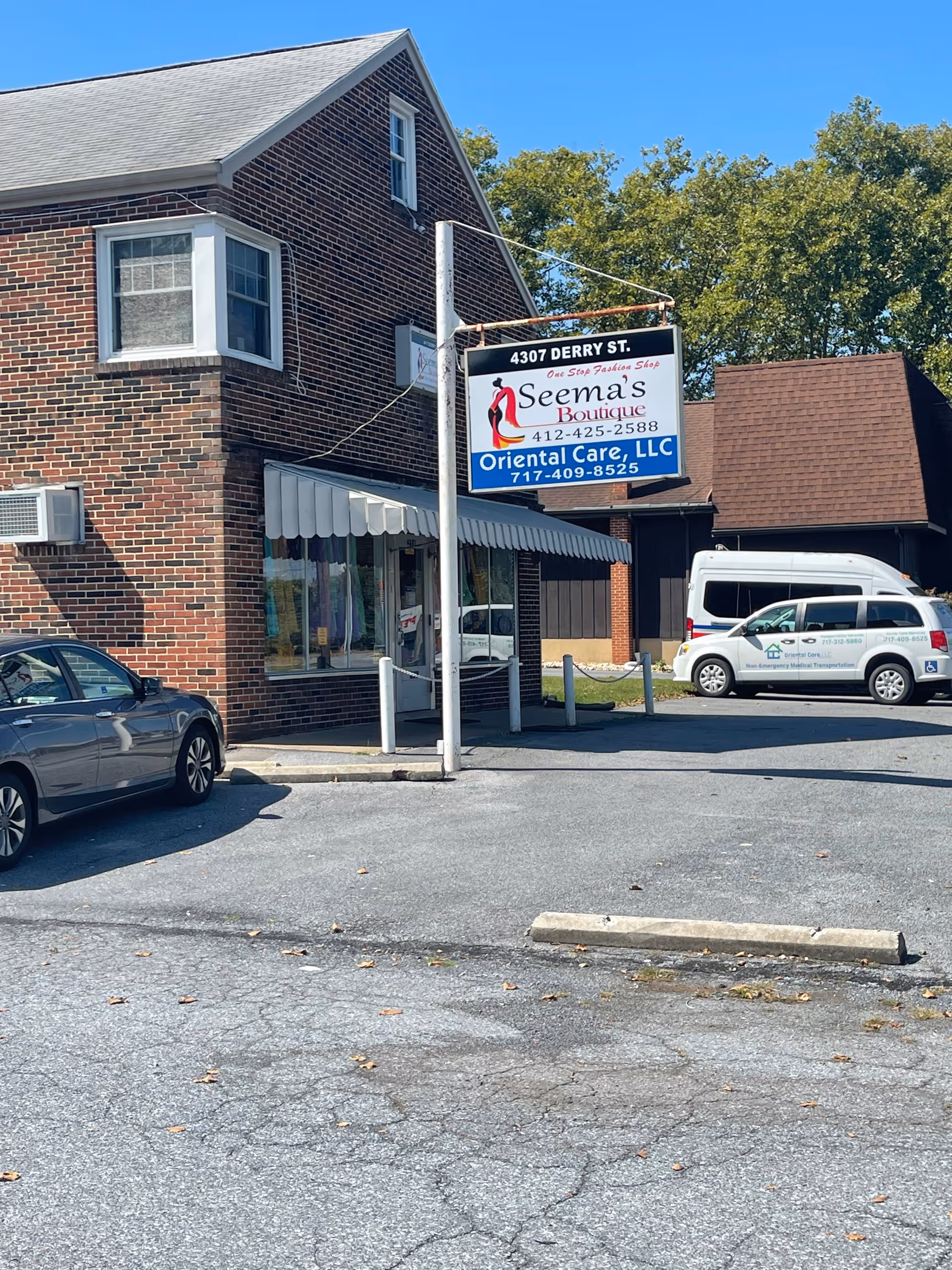Brick storefront with a hanging signboard for Seema's Boutique and Oriental Care, LLC.
