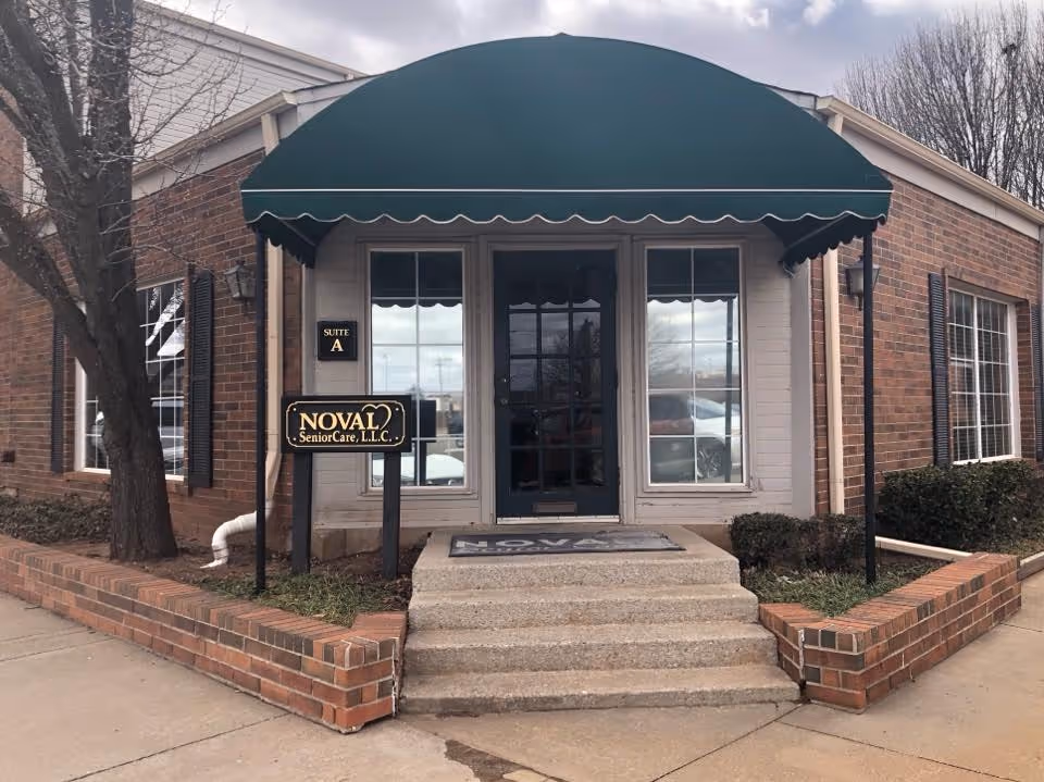 Brick building entrance with a green awning, double doors, and Noval SeniorCare LLC sign.