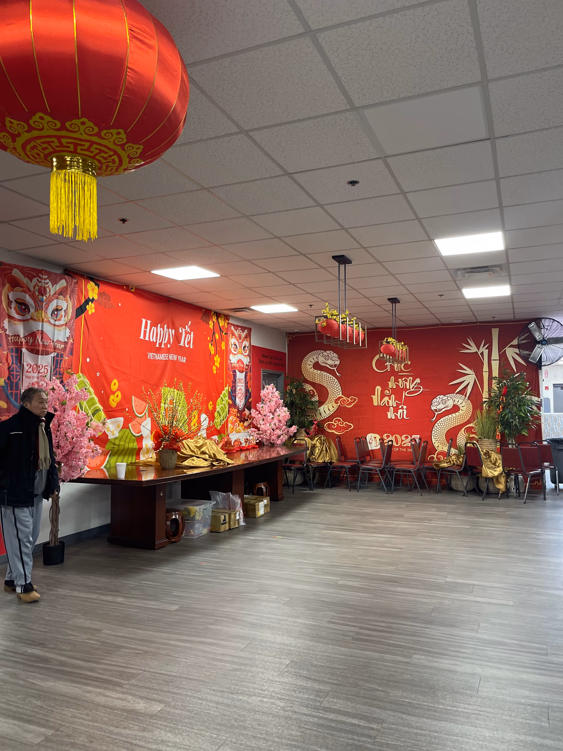 Indoor senior center hall decorated for Lunar New Year with red murals and a long table.