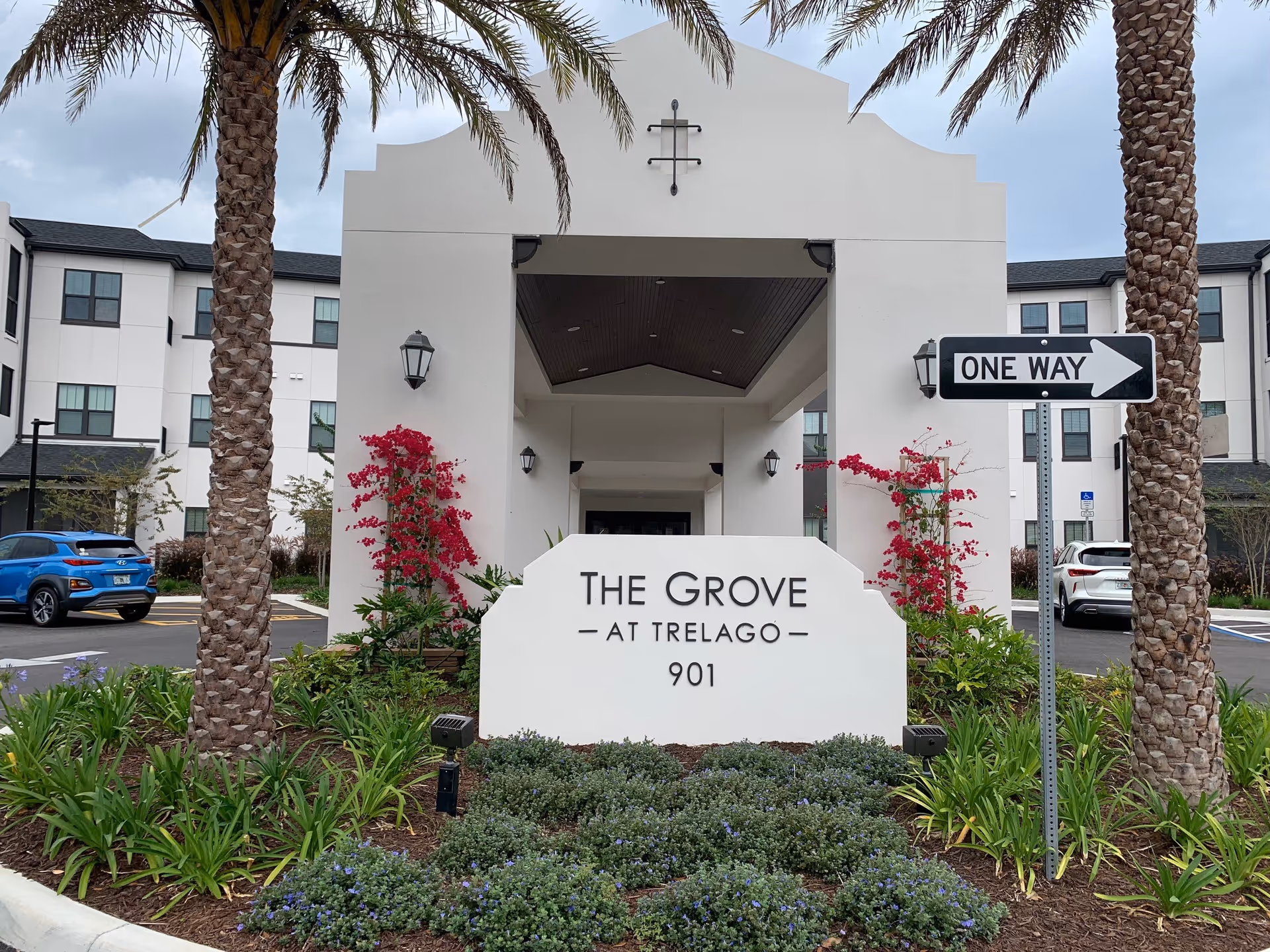 Exterior view of The Grove at Trelago entrance with palm trees and sign