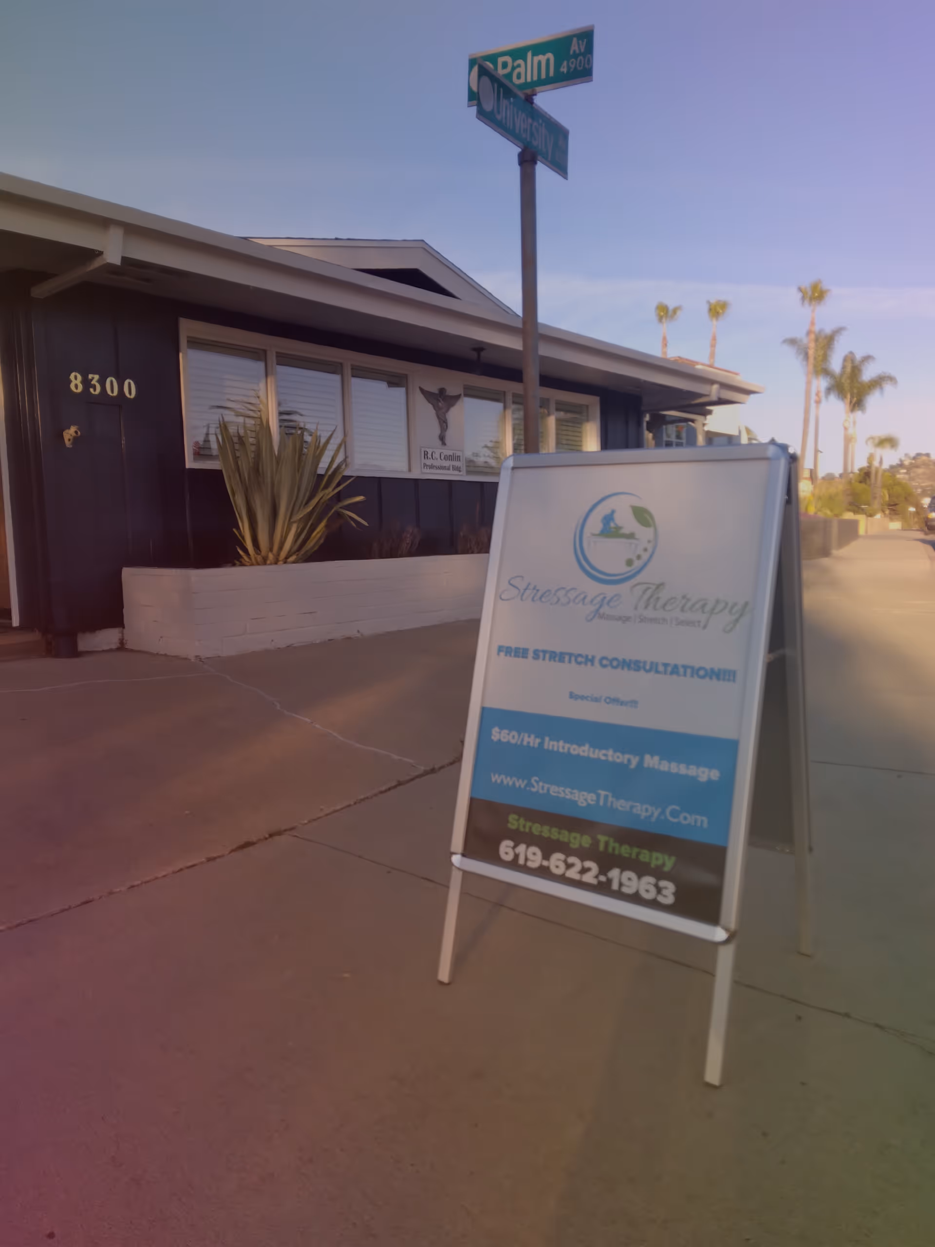 Exterior view of a small building with a Stressage Therapy signboard at the sidewalk.