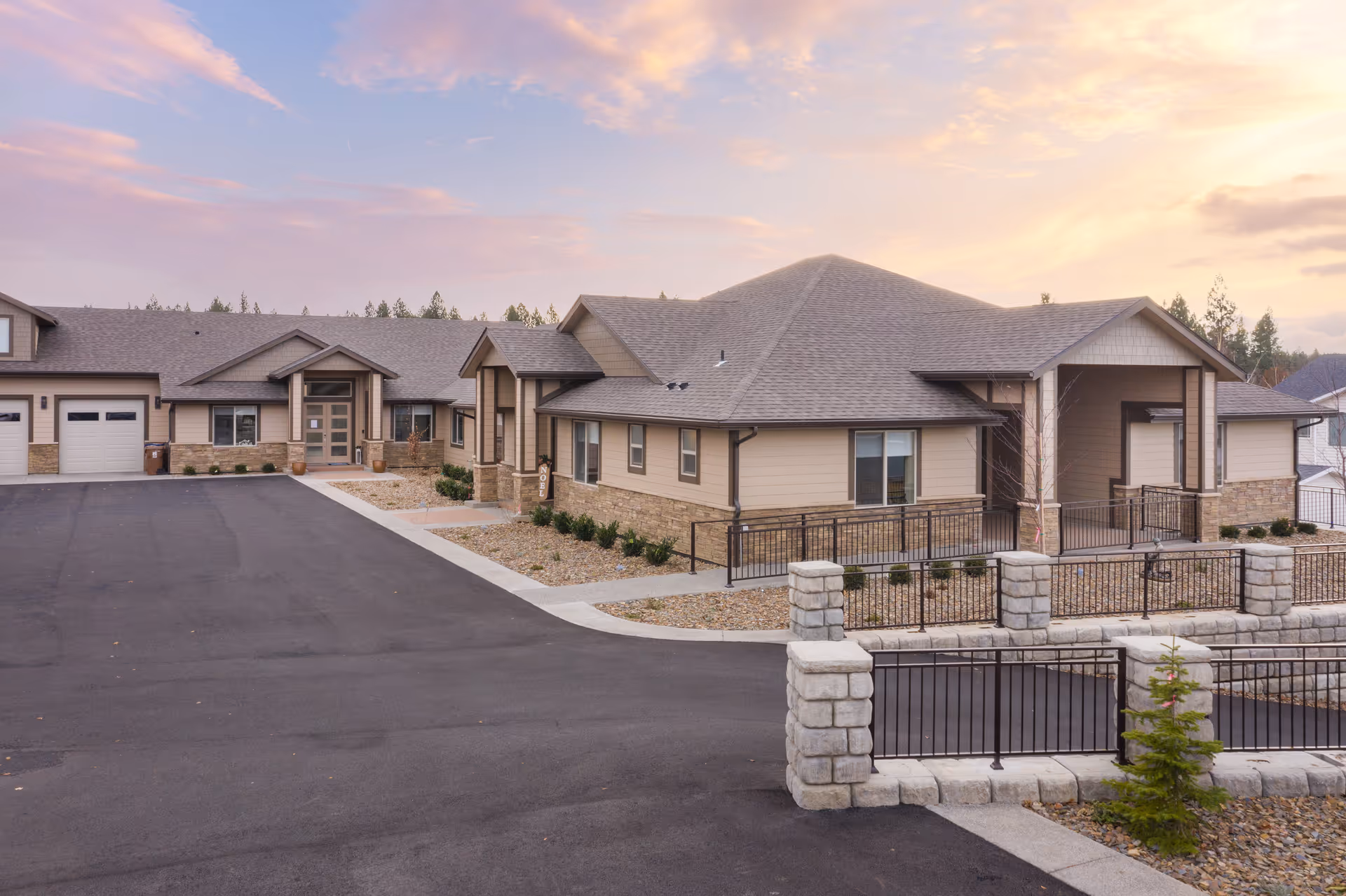 Exterior view of a single-story senior living facility with a gated entrance and landscaped grounds.