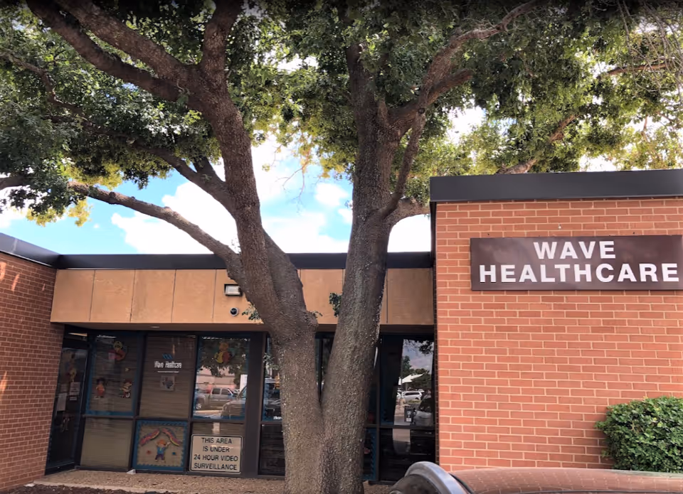Exterior view of Wave Healthcare building front with a large tree in foreground.
