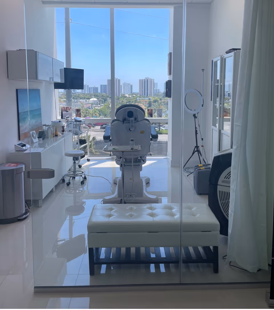 Bright, modern clinical room with a reclining chair, glass wall, and city view.