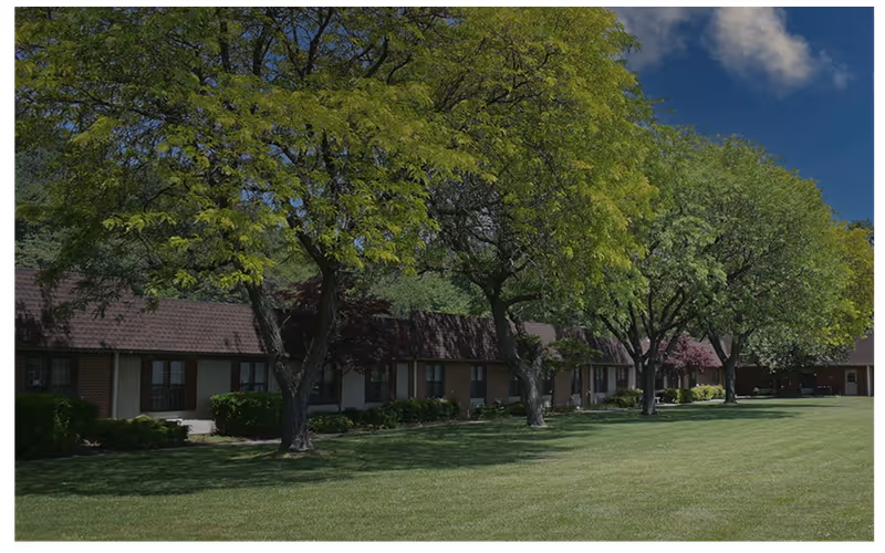 Exterior view of a single-story brick building with trees and well-kept lawn.