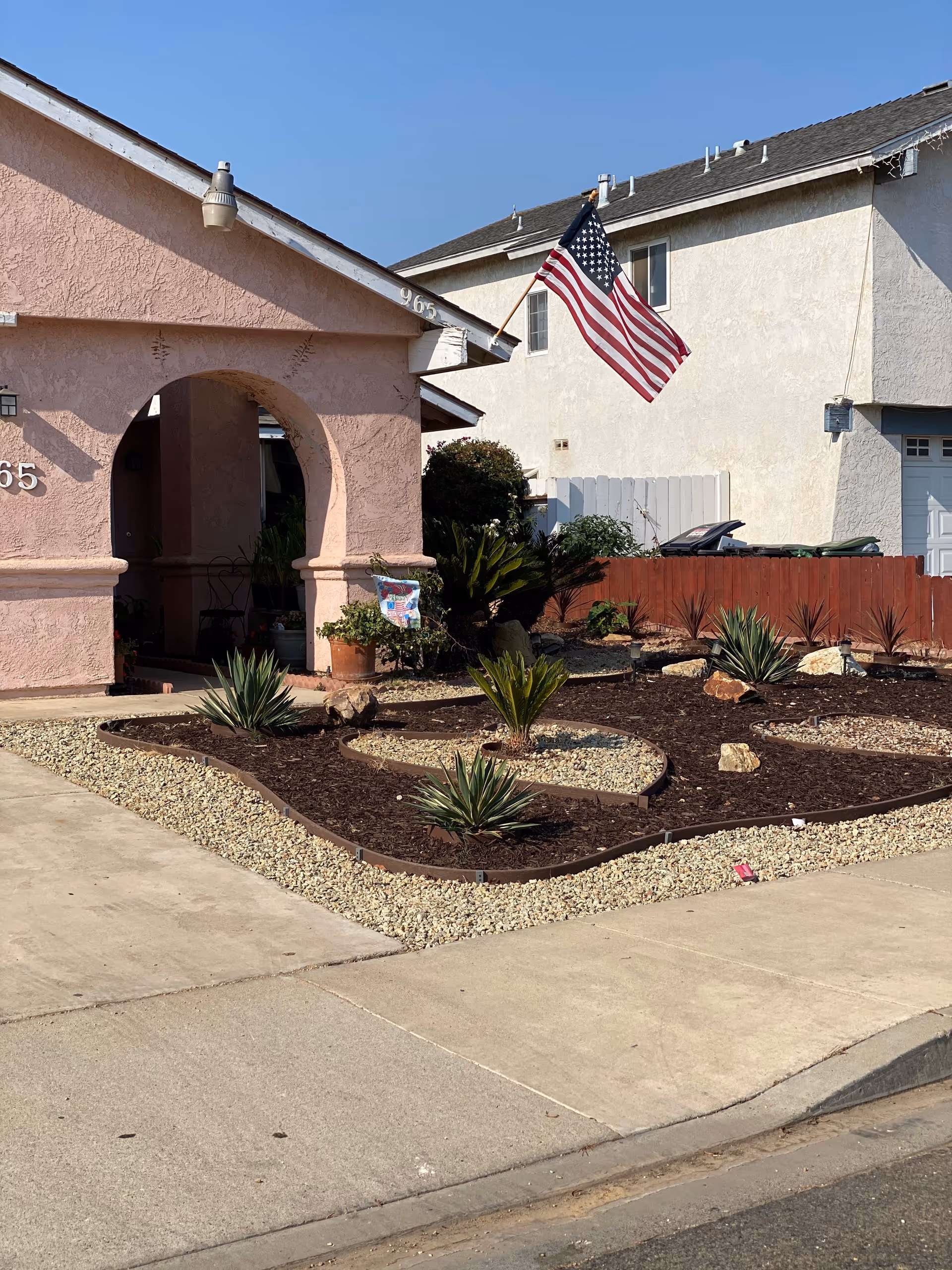 Facade of Villa-Care Home IV with arch entrance, desert landscaping, and an American flag.
