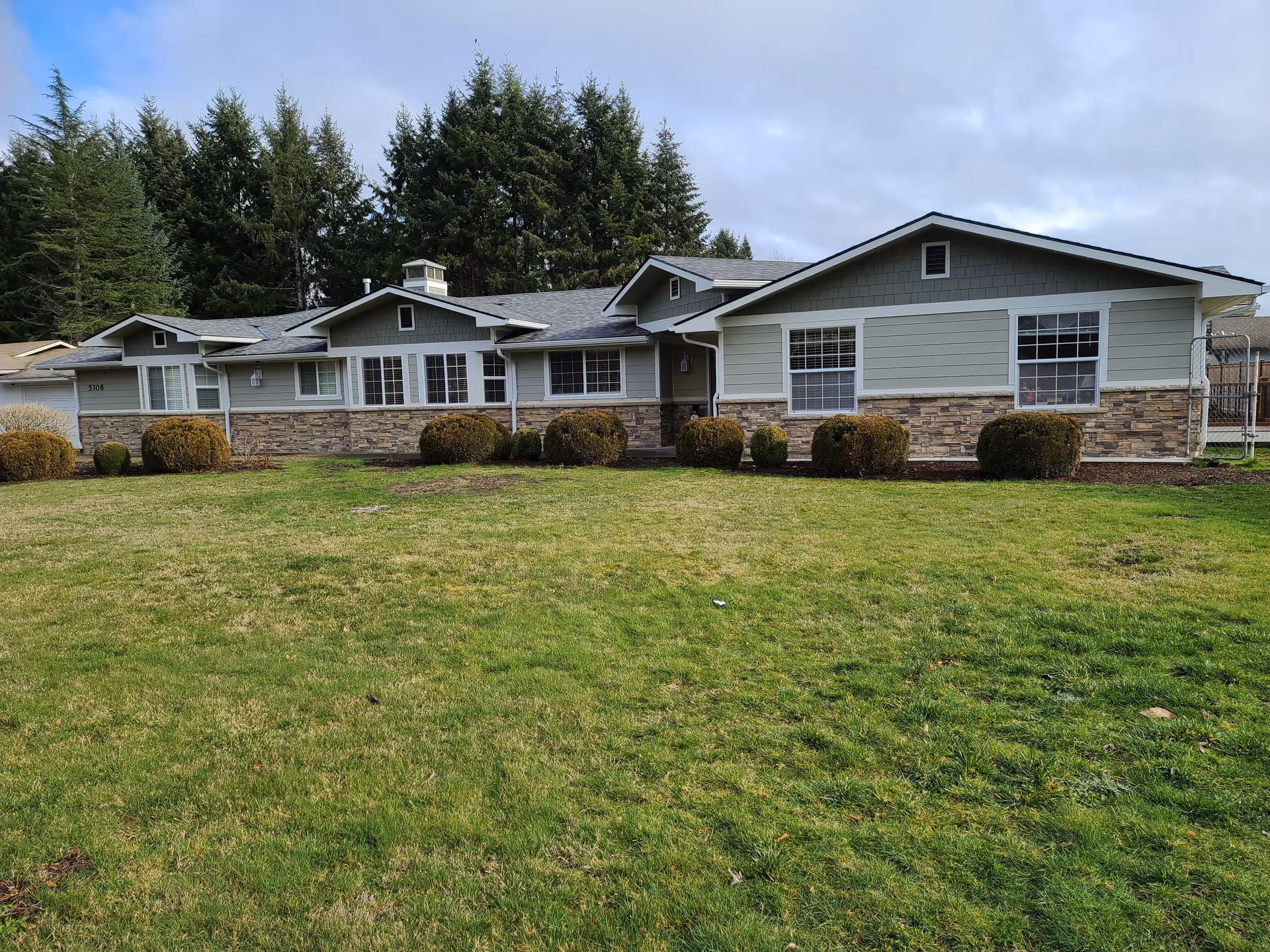 Front view of a single-story senior home with stone facade and a manicured lawn.