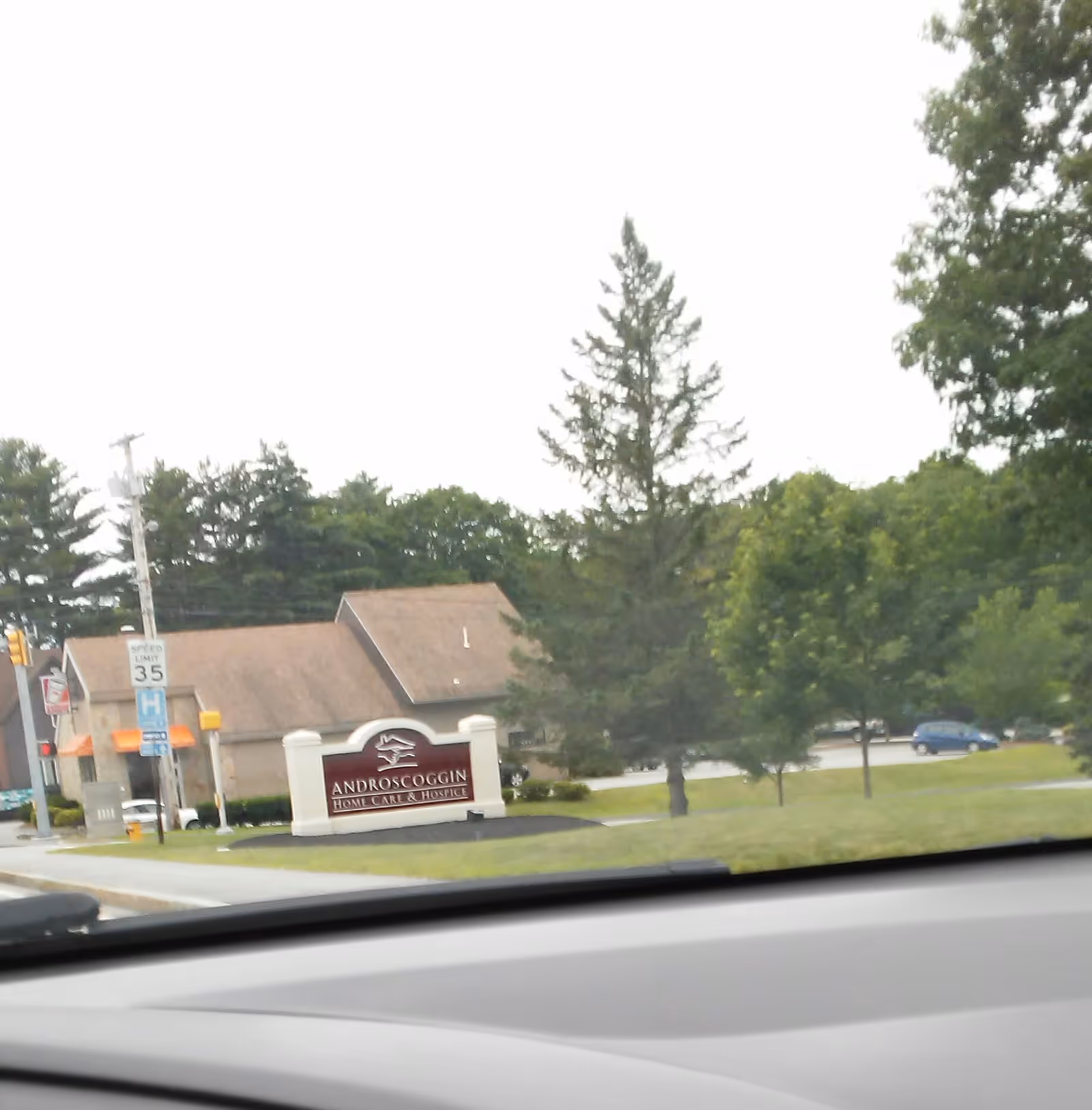 Front view of Androscoggin Home Care & Hospice building sign and entrance with trees