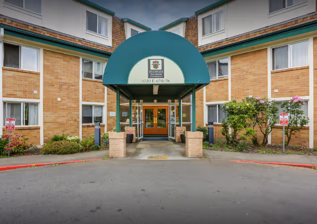 Front entrance of Peoples Senior Living building with a green canopy and brick exterior.