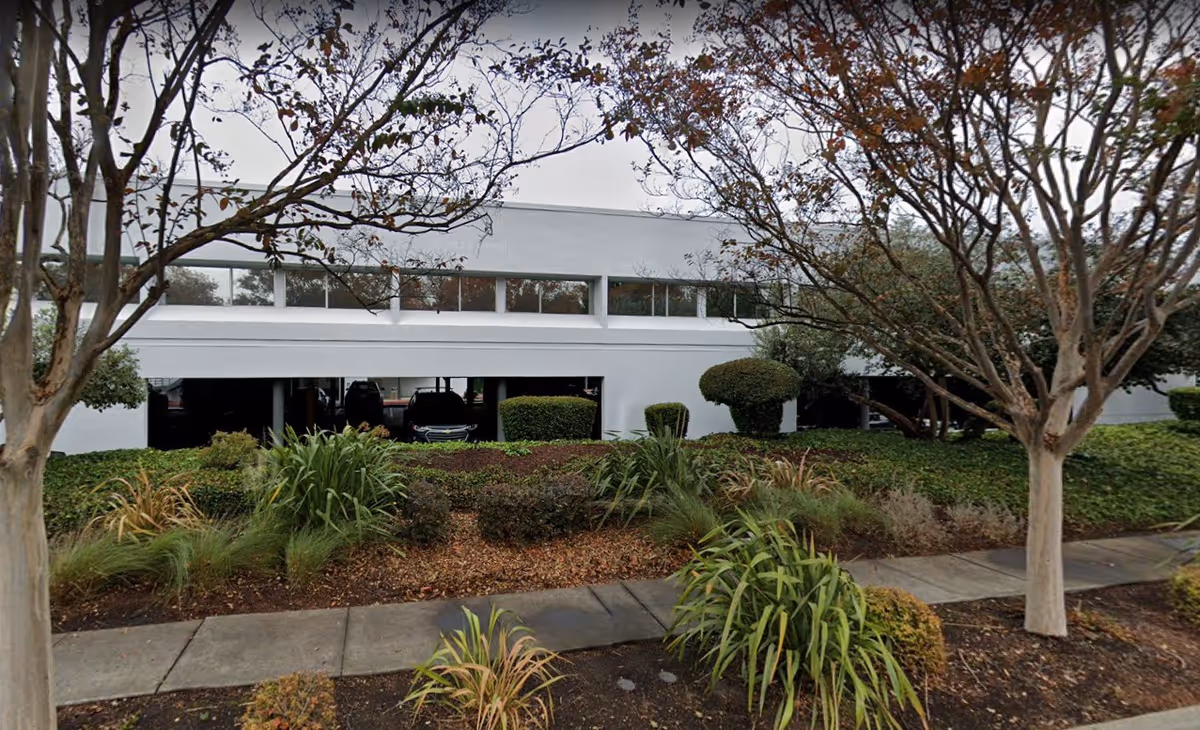 Front view of a white modern senior living facility with manicured shrubs and trees.