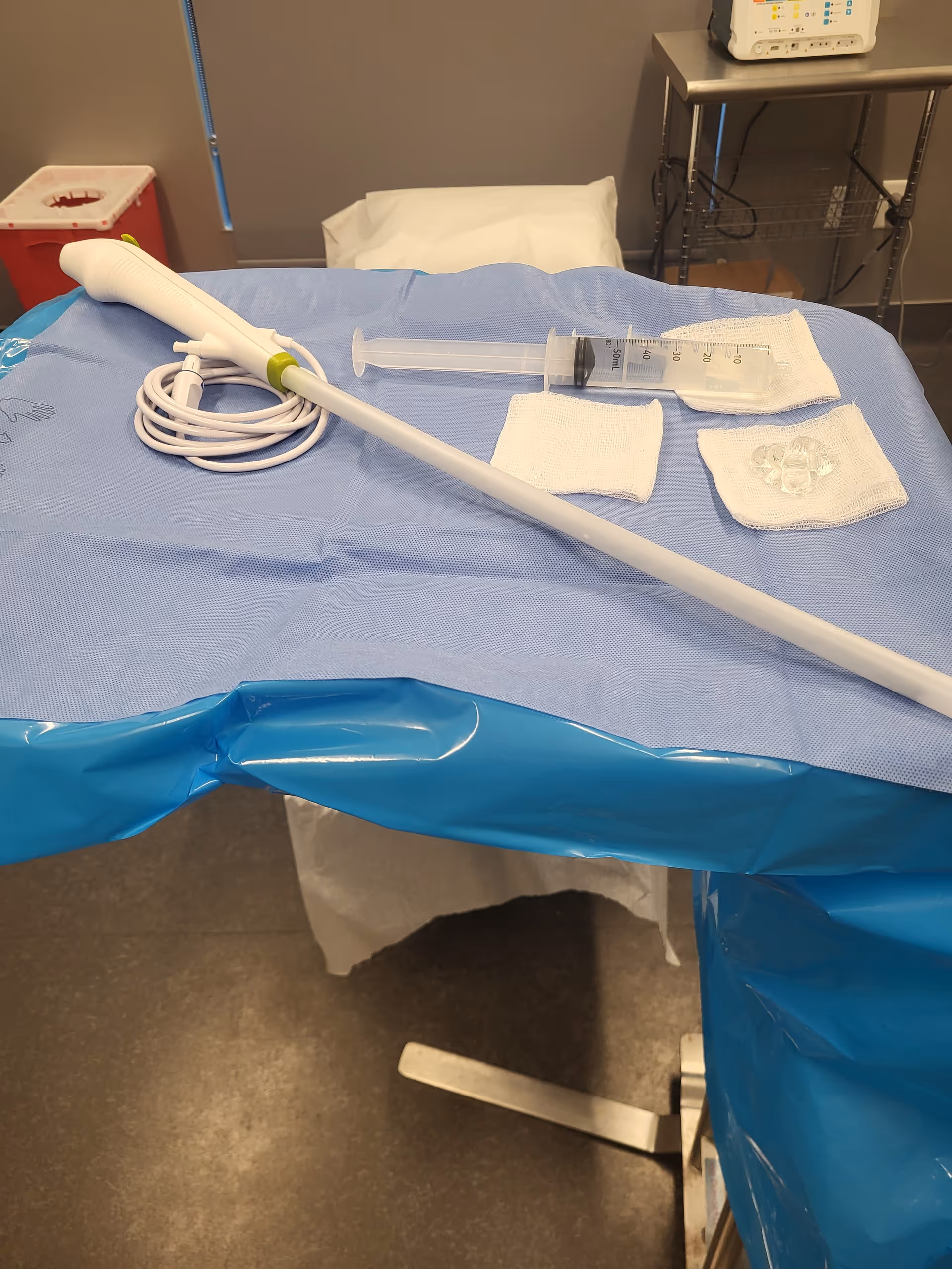 Medical procedure setup on a sterile table with syringe, tubing, and disposable supplies.