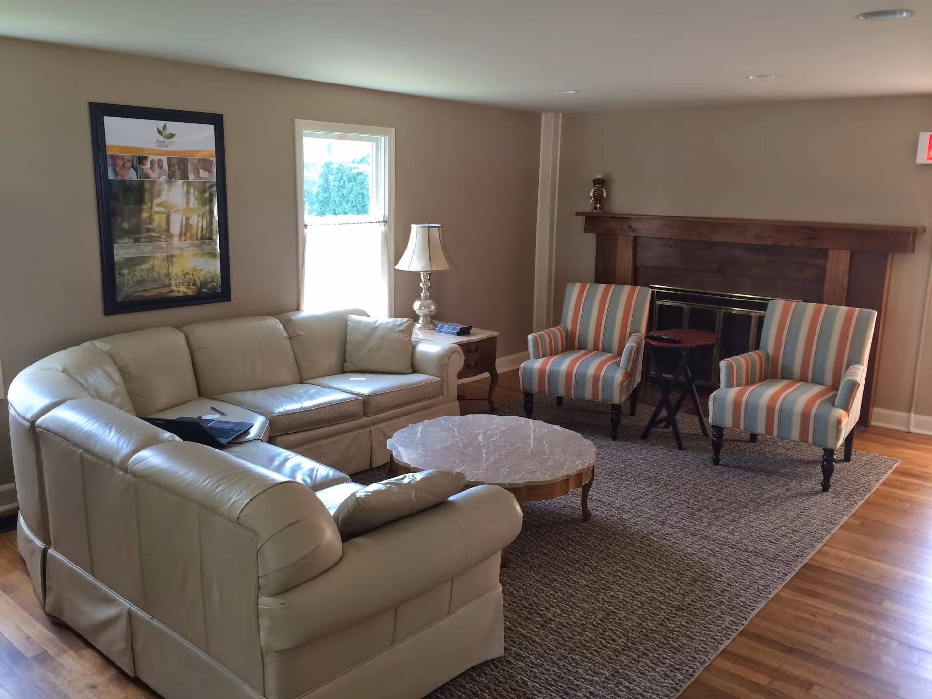 Cream leather sectional sofa and striped chairs surround a round coffee table in a living room.