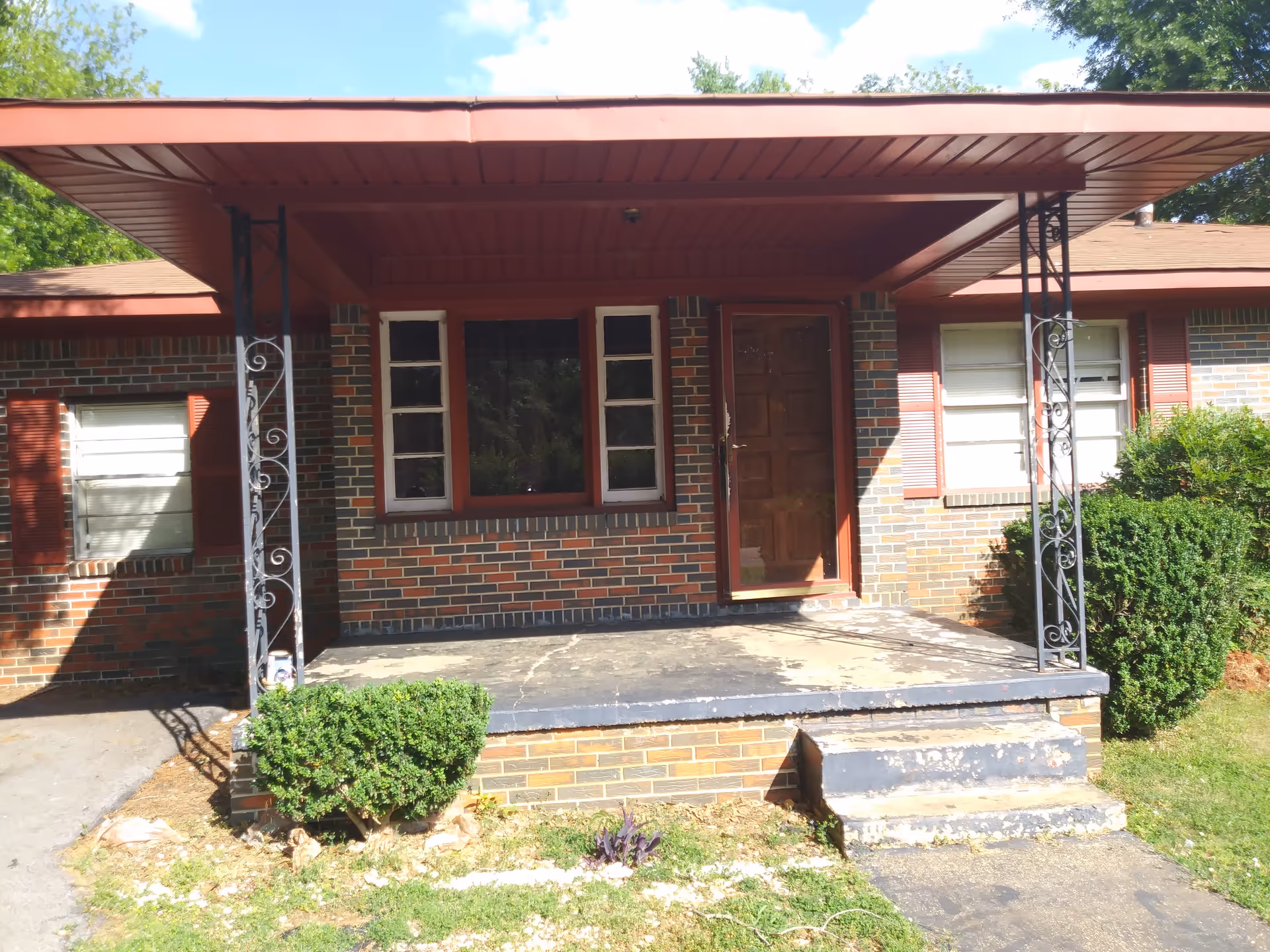 Brick front entrance of a single-story building with a covered porch and steps.