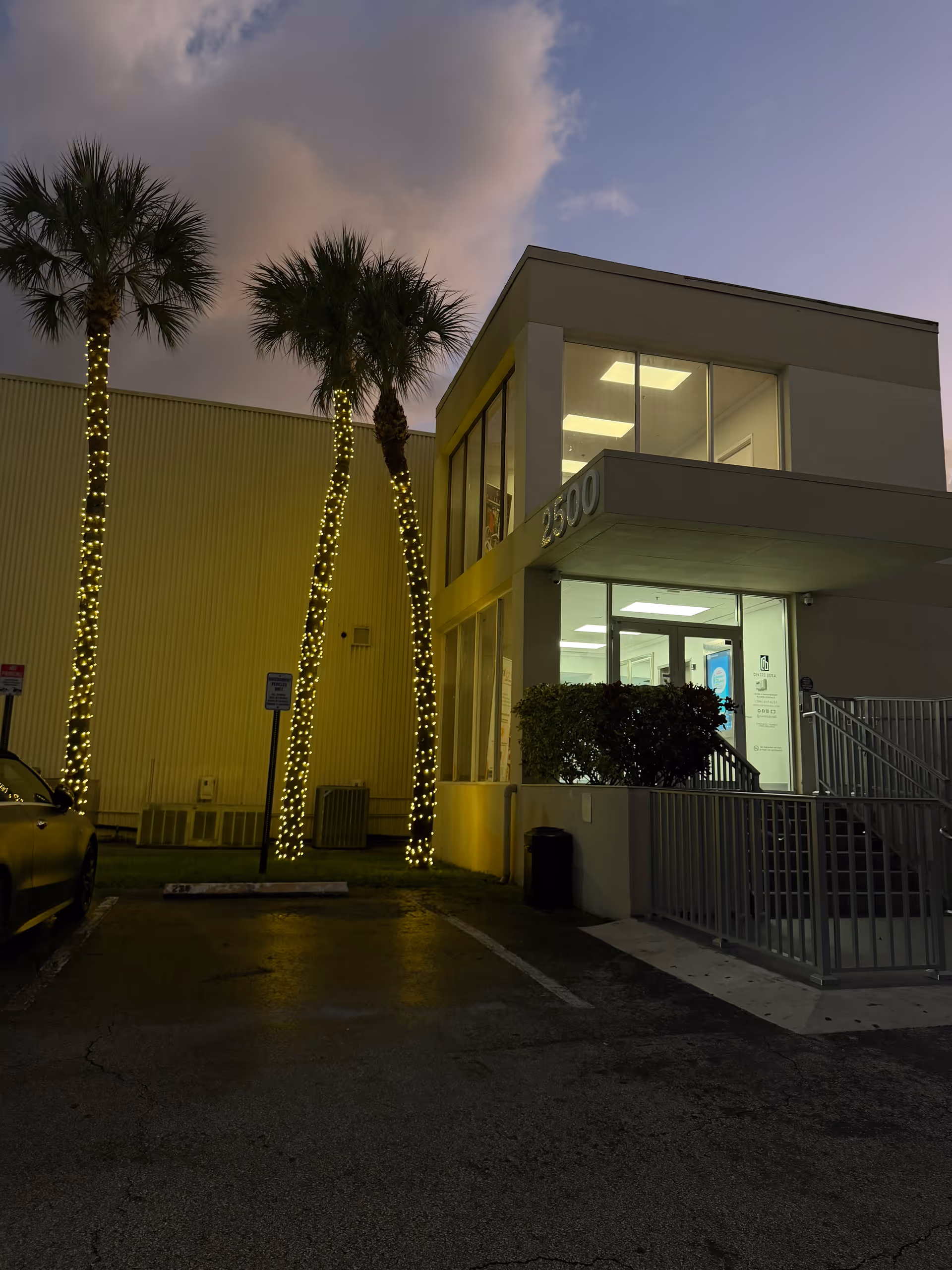 Exterior view of Nosa Home Health LLC entrance with illuminated palm trees at dusk.