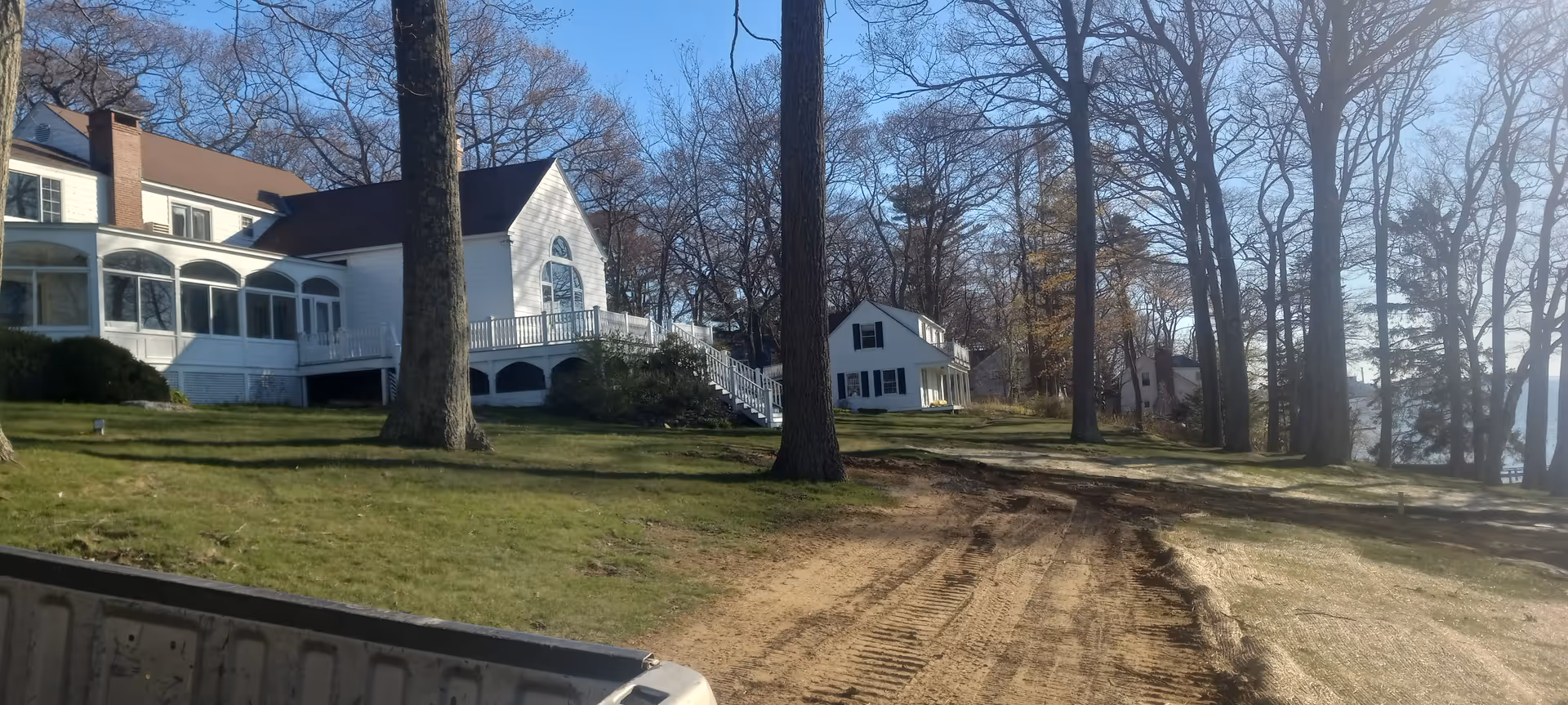 White, two-story senior housing building with porches, trees, and a dirt driveway on a grassy yard.