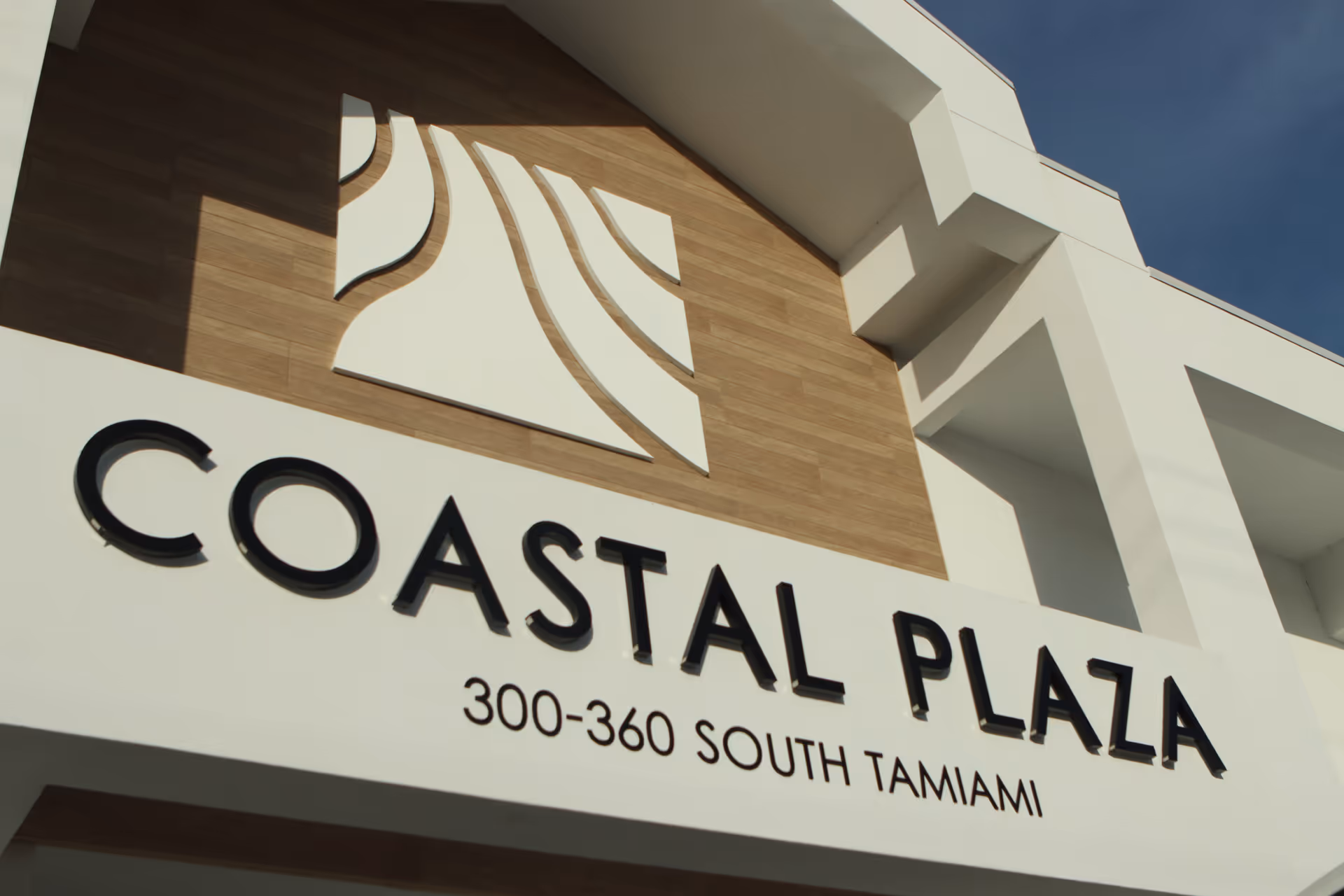 Exterior view of a building front with Coastal Plaza signage and architecture.