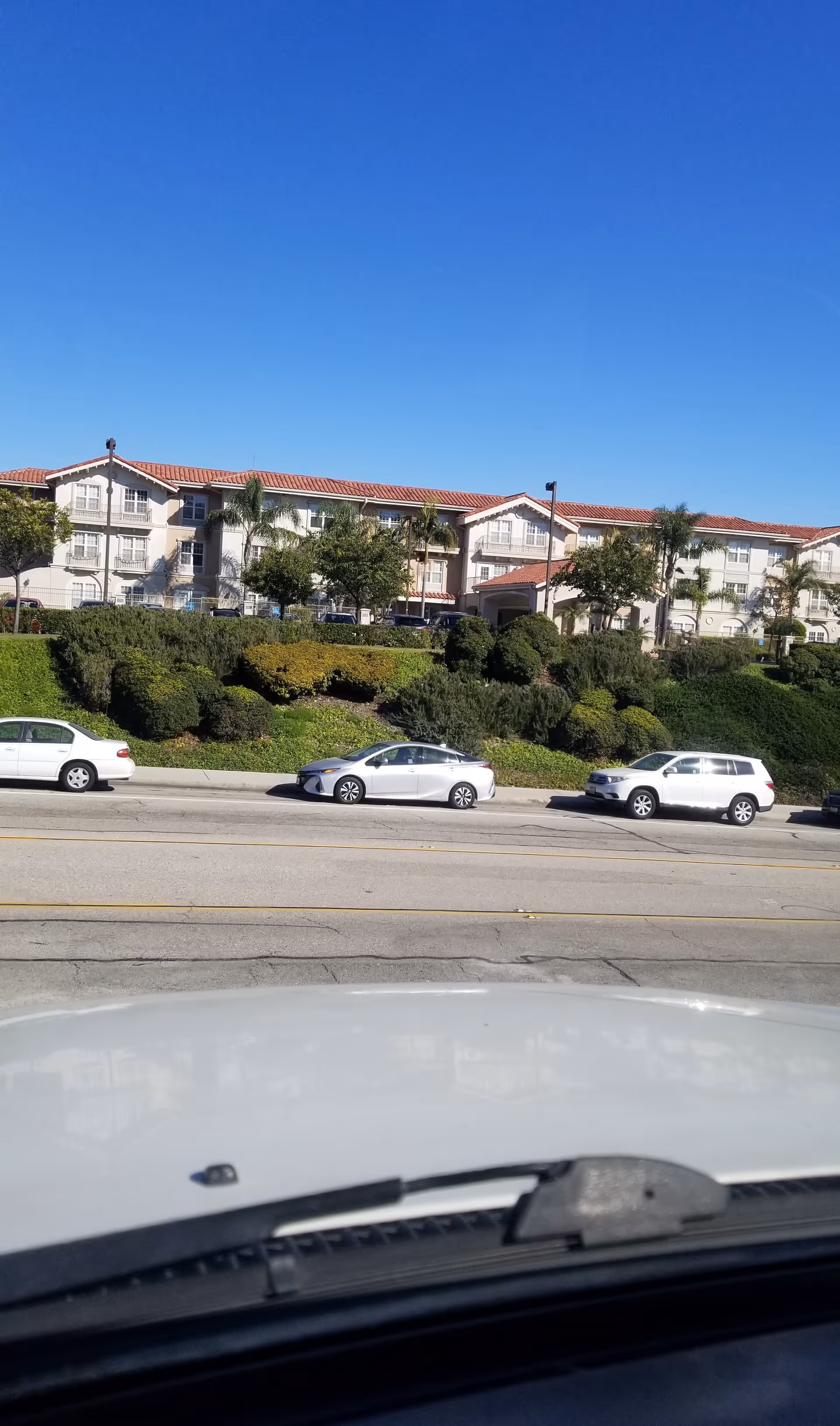 Exterior view of Belmont Village Senior Living Rancho Palos Verdes with cars and landscaping.