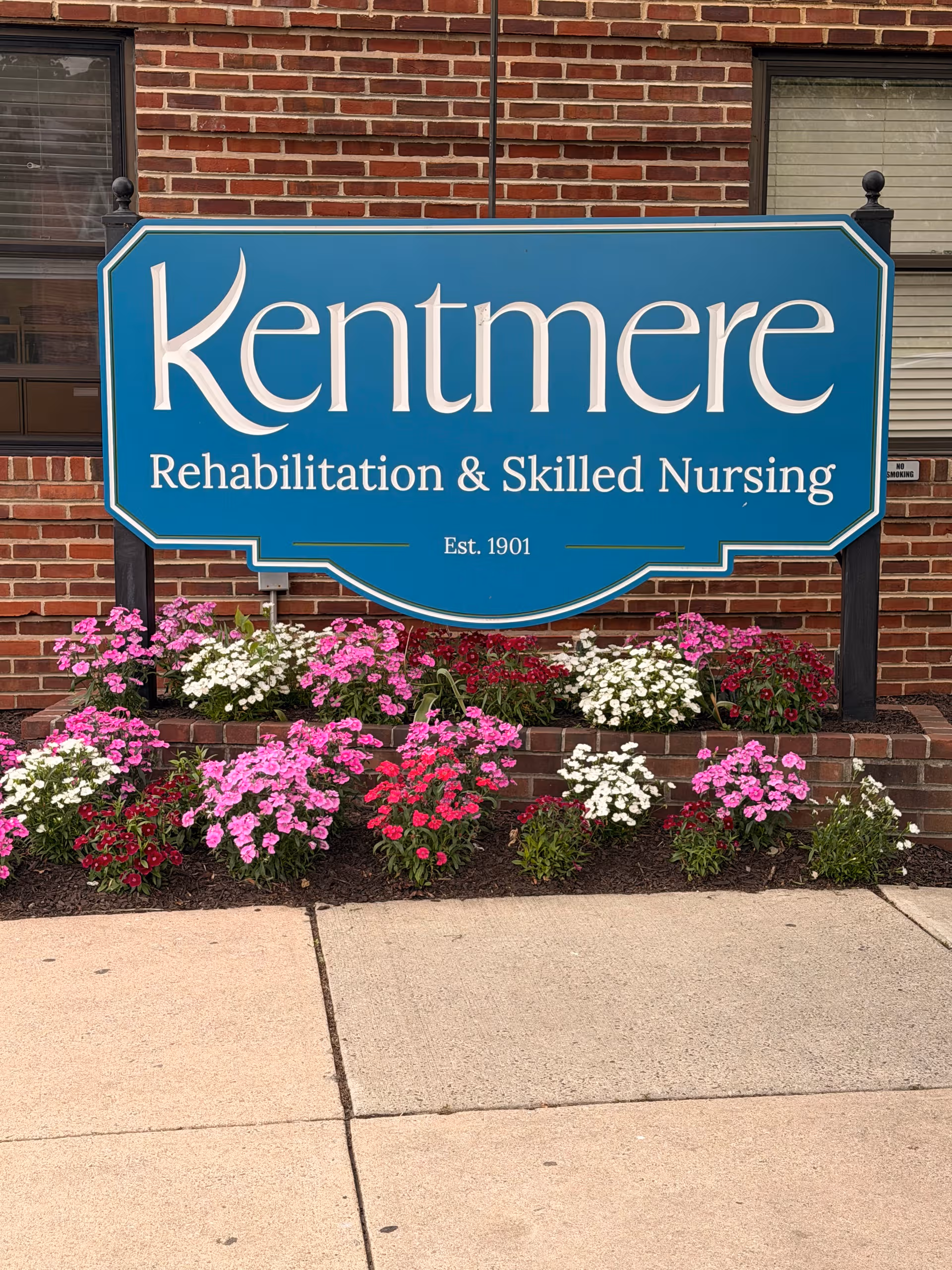 Kentmere Rehabilitation sign on brick front with colorful flowers