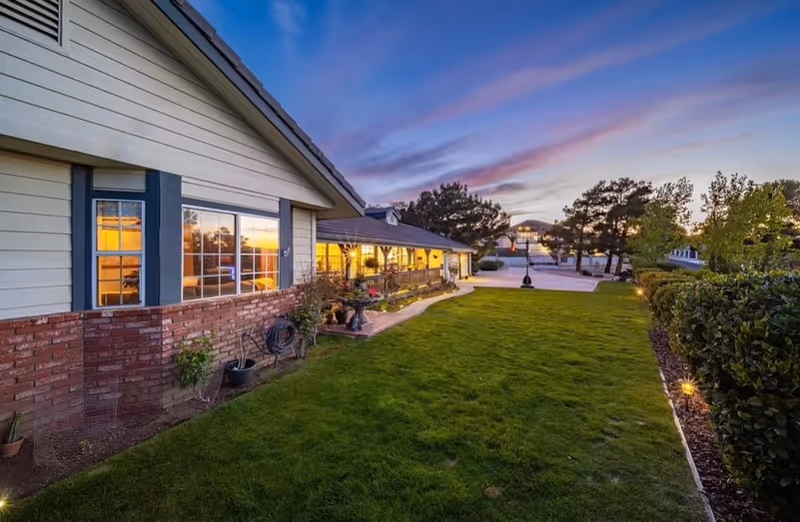 Exterior view of Instacare, A Place Called Home at dusk, showing lawn, walkway, and building facade.