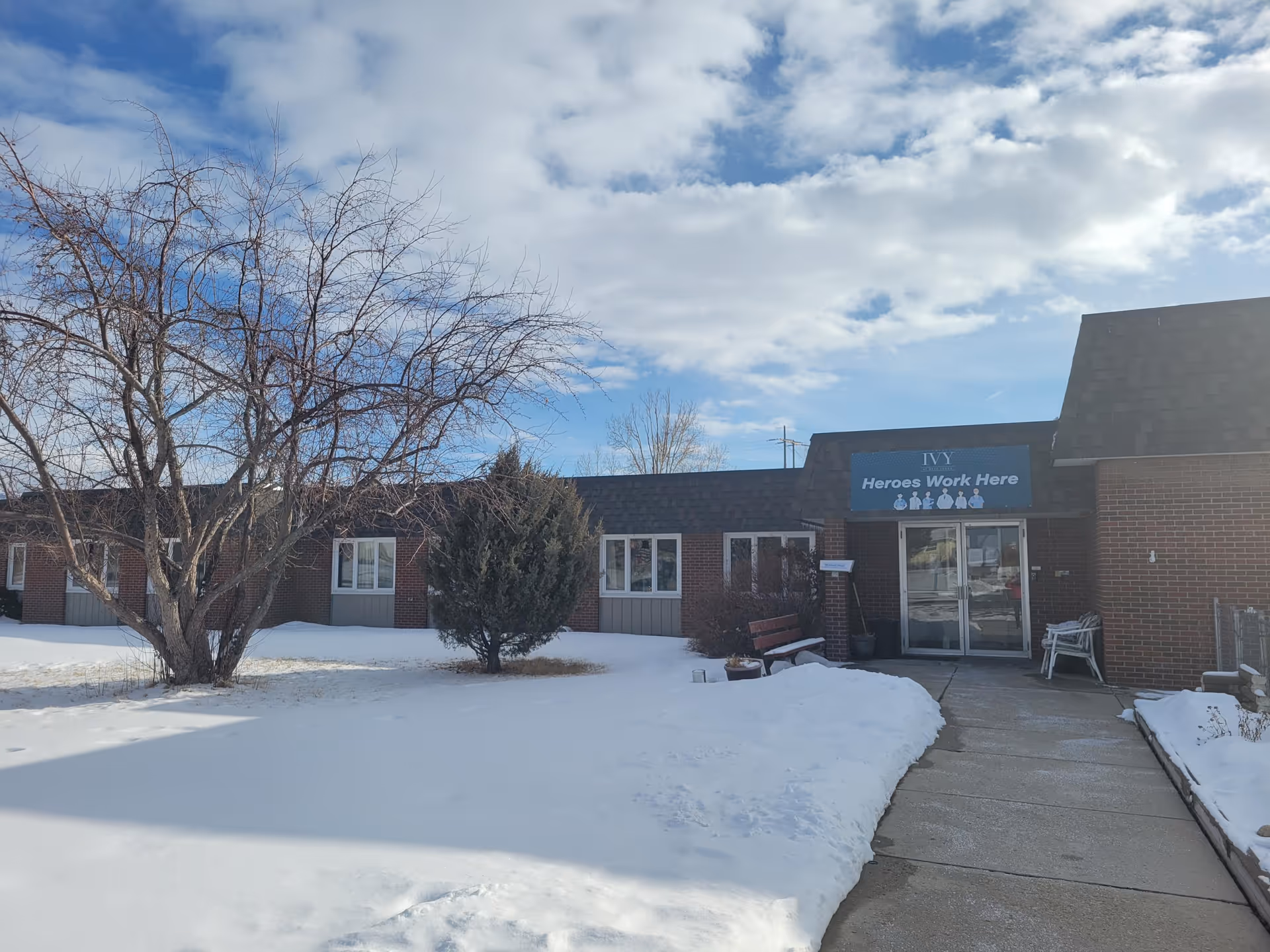 Exterior view of The Ivy at Deer Lodge entrance with snow and leafless trees.