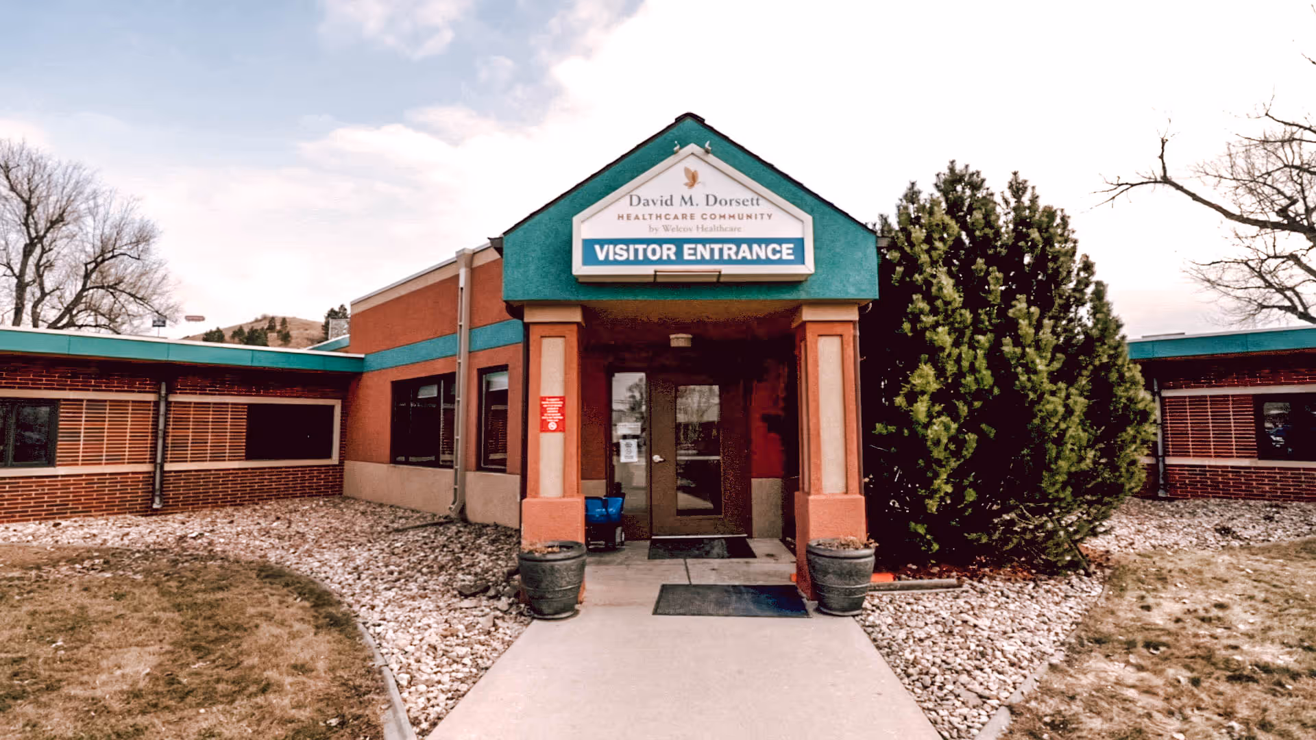 Front visitor entrance of a healthcare building with a 'Visitor Entrance' sign above the doorway.