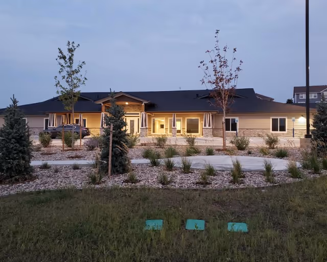 Beige single-story assisted living facility with landscaped front yard and patio seating