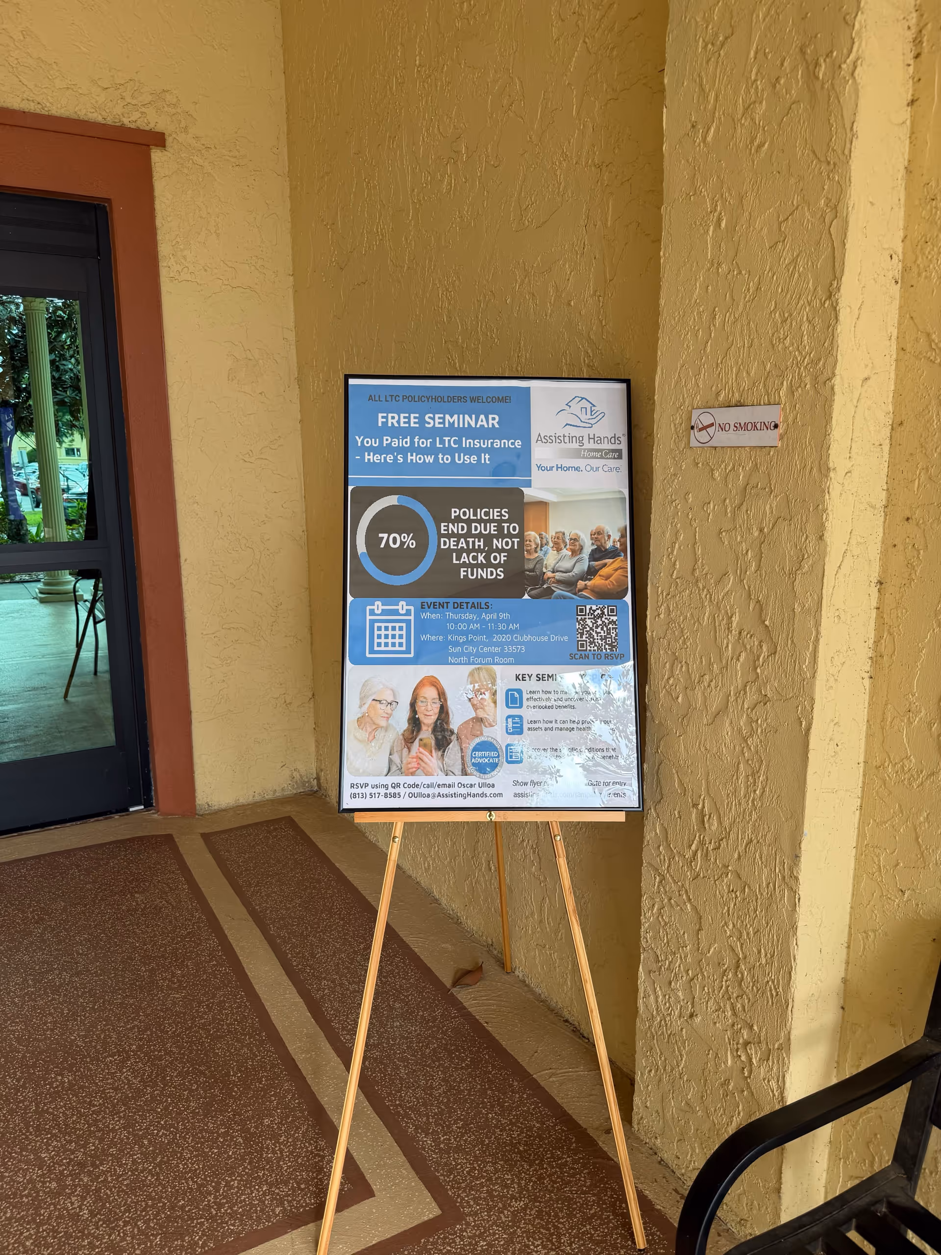 Poster on an easel advertising a free seminar beside a doorway in a tan hallway