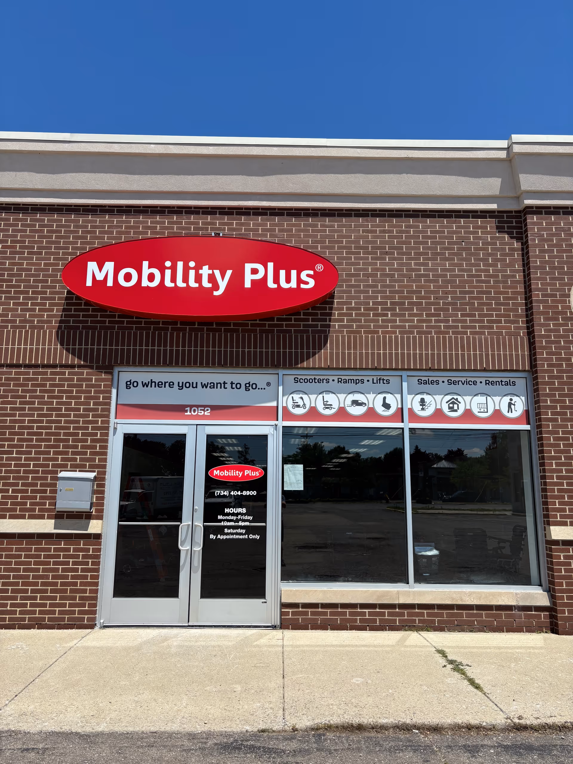 Brick storefront with Mobility Plus red oval sign and glass doors