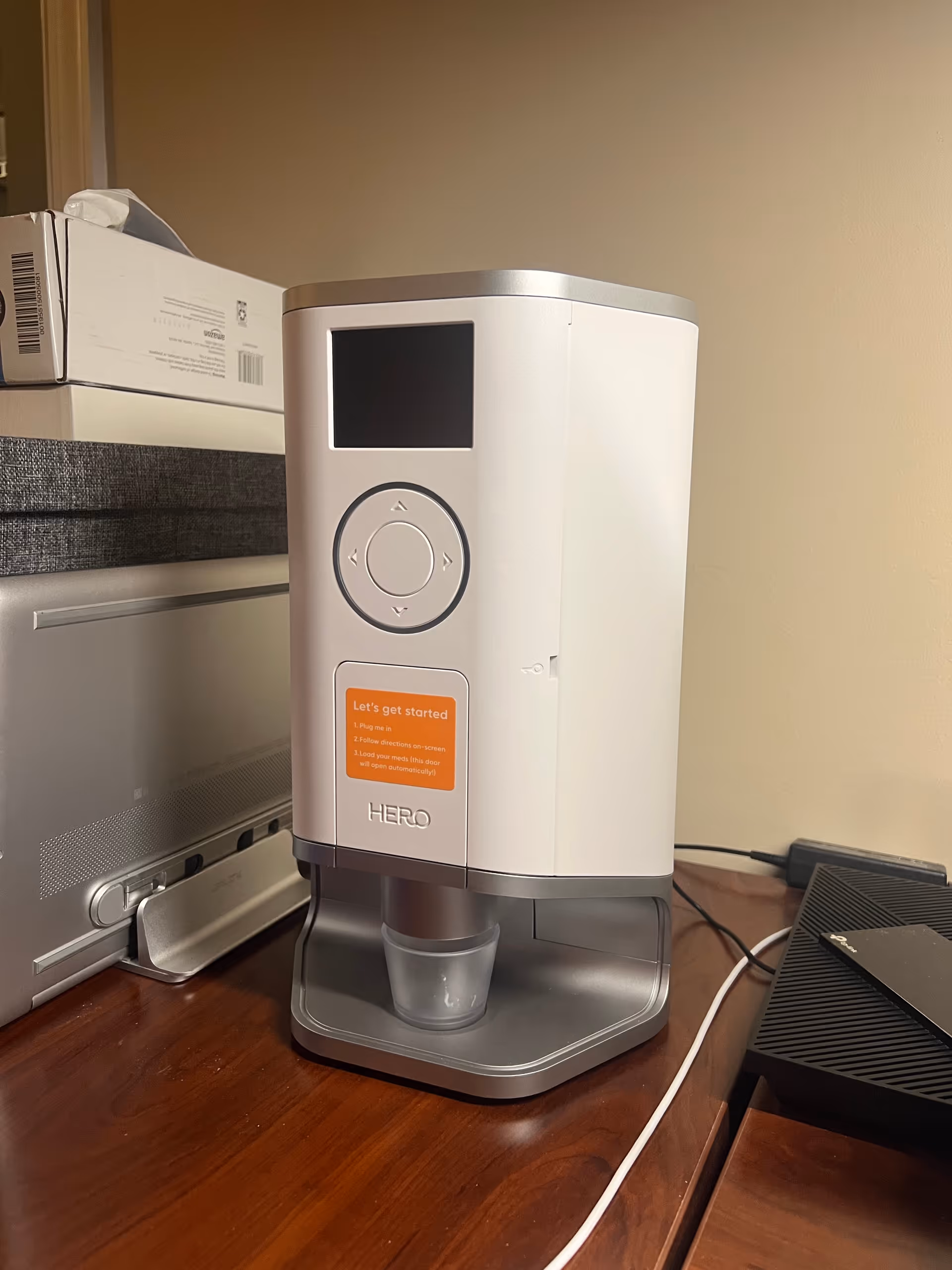 White Hero Health beverage dispenser on a wooden desk with a cup.