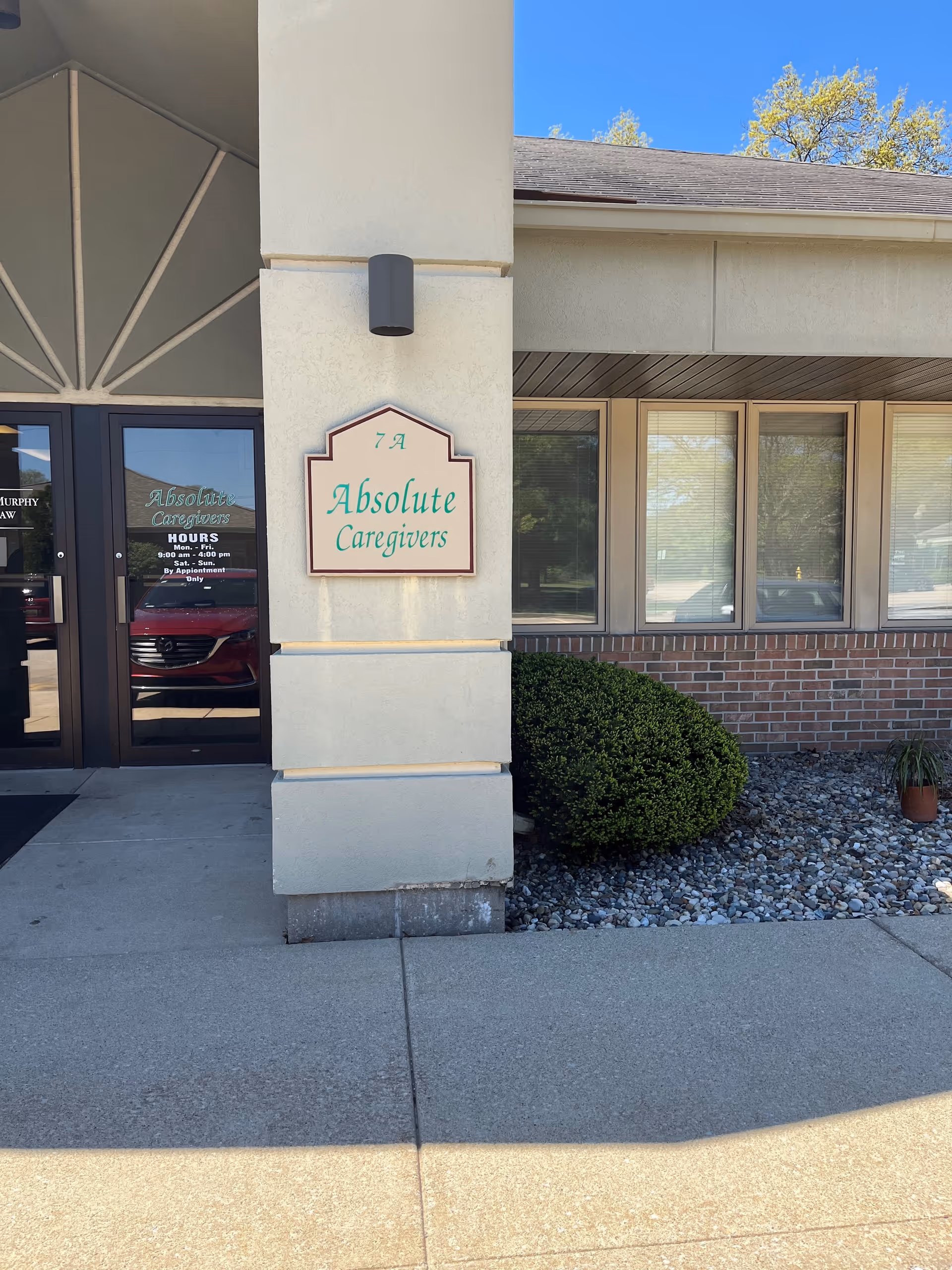 Front entrance of Absolute Caregivers with sign, windows, and landscaped frontage.