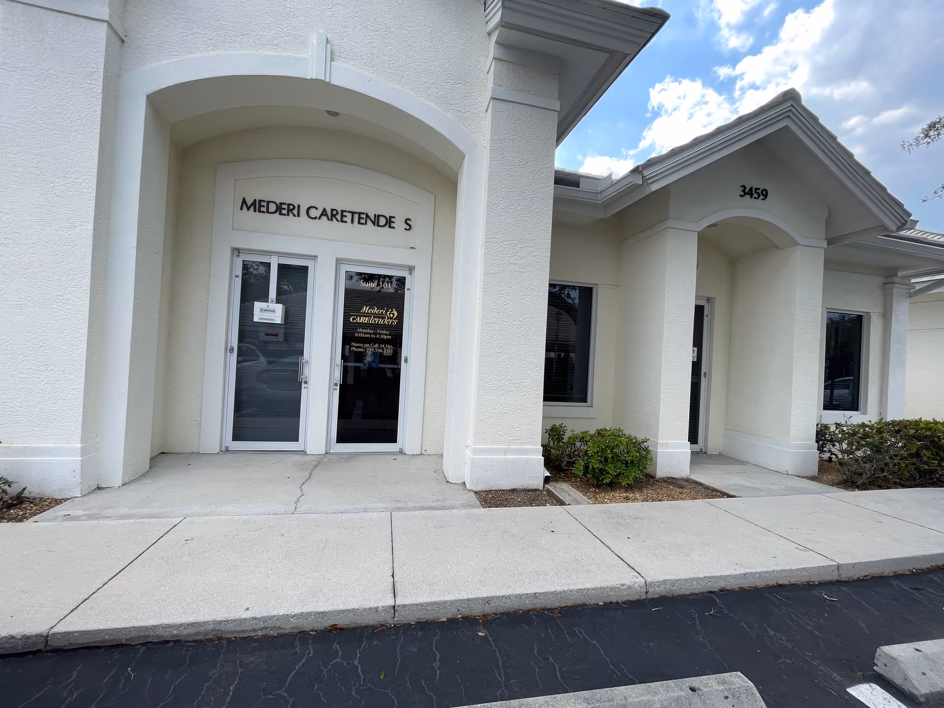 White building front with arched entrance and glass double doors.
