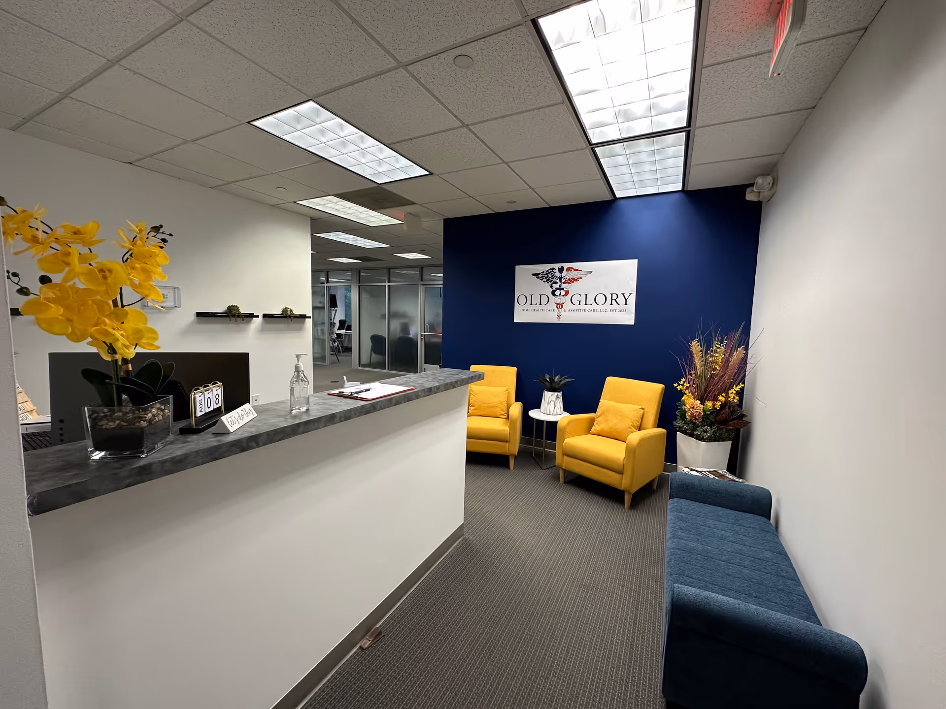 Reception area with blue accent wall, yellow chairs, and a counter at Old Glory.