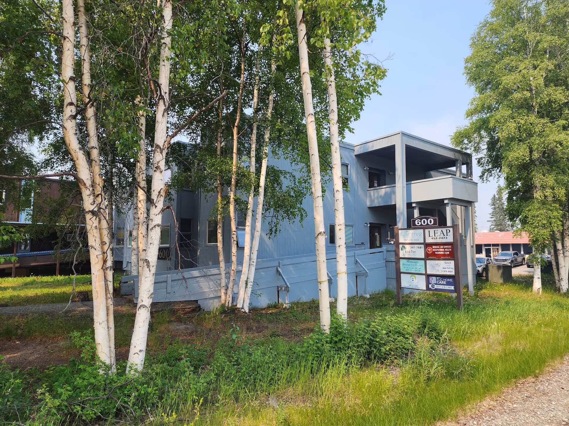 Blue exterior of a senior care building with signage and trees.