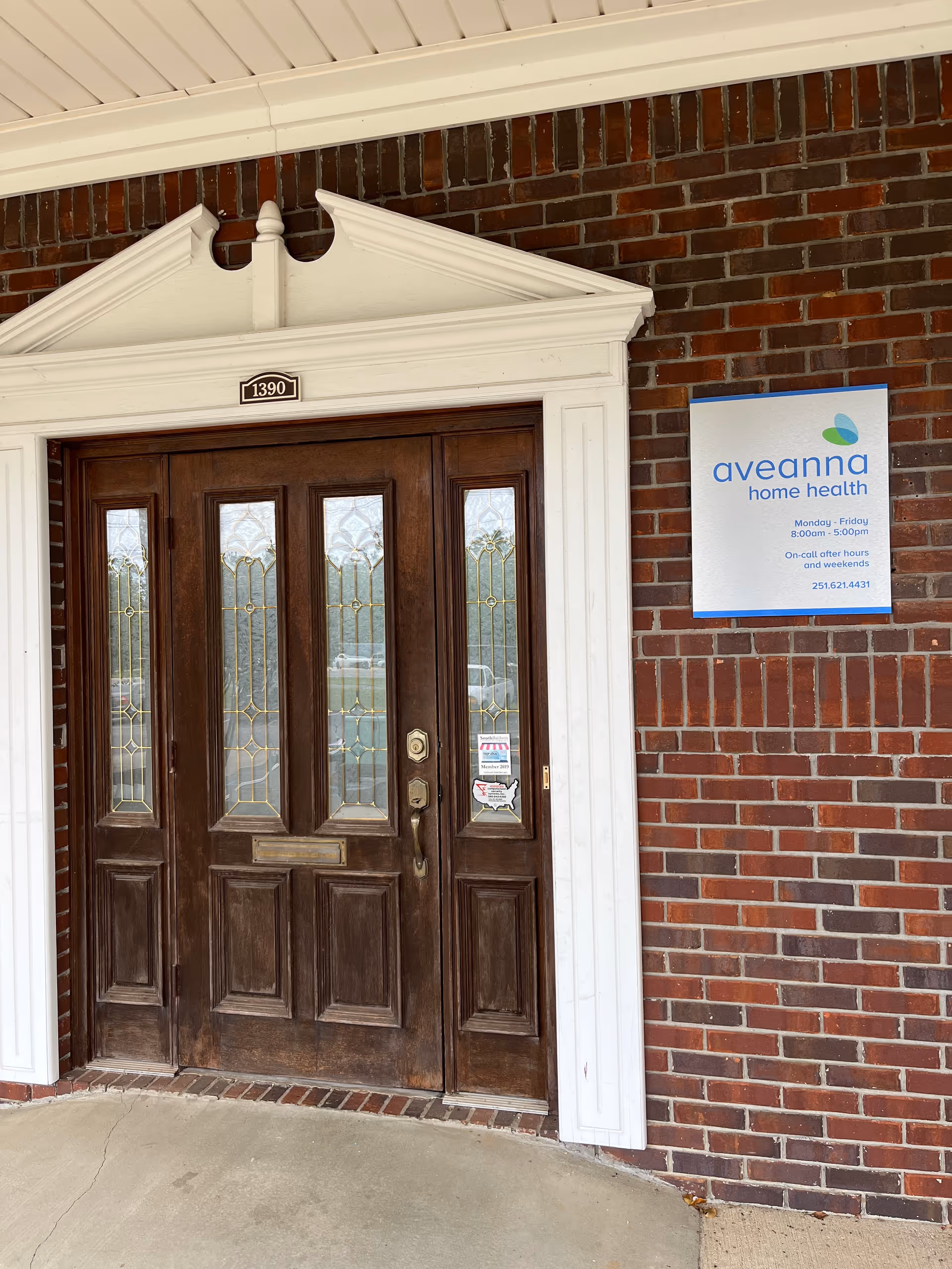Exterior view of Aveanna Home Health of Foley entrance with a brick wall and wooden door.