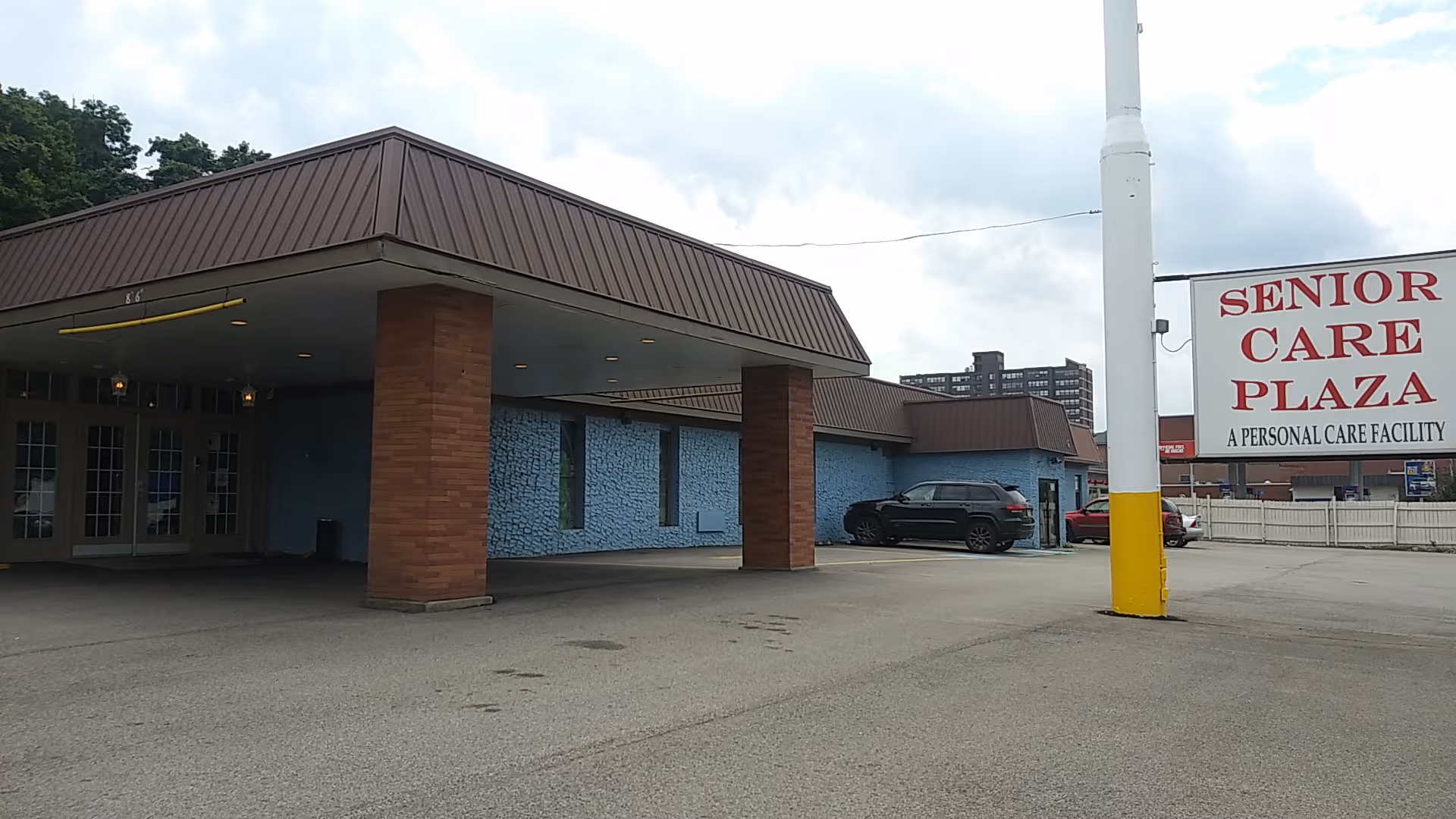 Exterior view of Senior Care Plaza building with covered entrance and parking area.