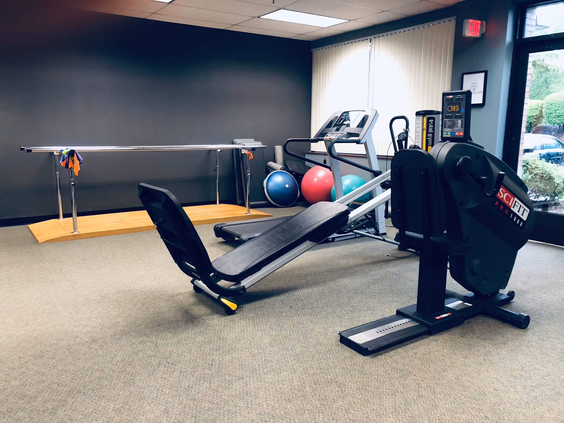 Interior fitness room with leg press, treadmill, exercise balls, and a ballet barre.
