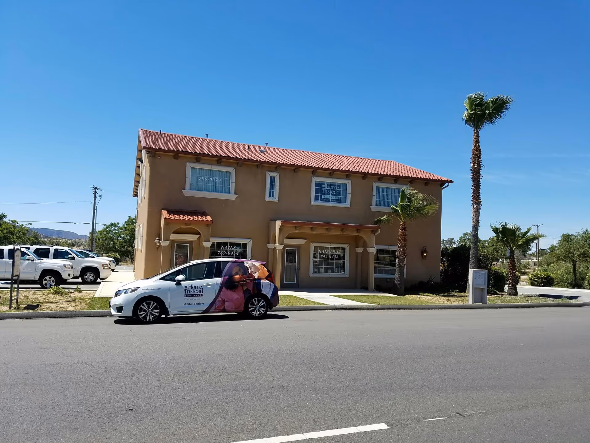 Two-story tan building with a Home Instead van parked in front on a sunny day.