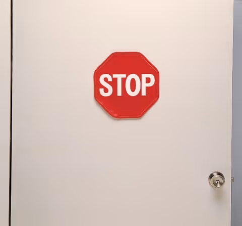 White interior door with a red octagonal STOP sign mounted on it