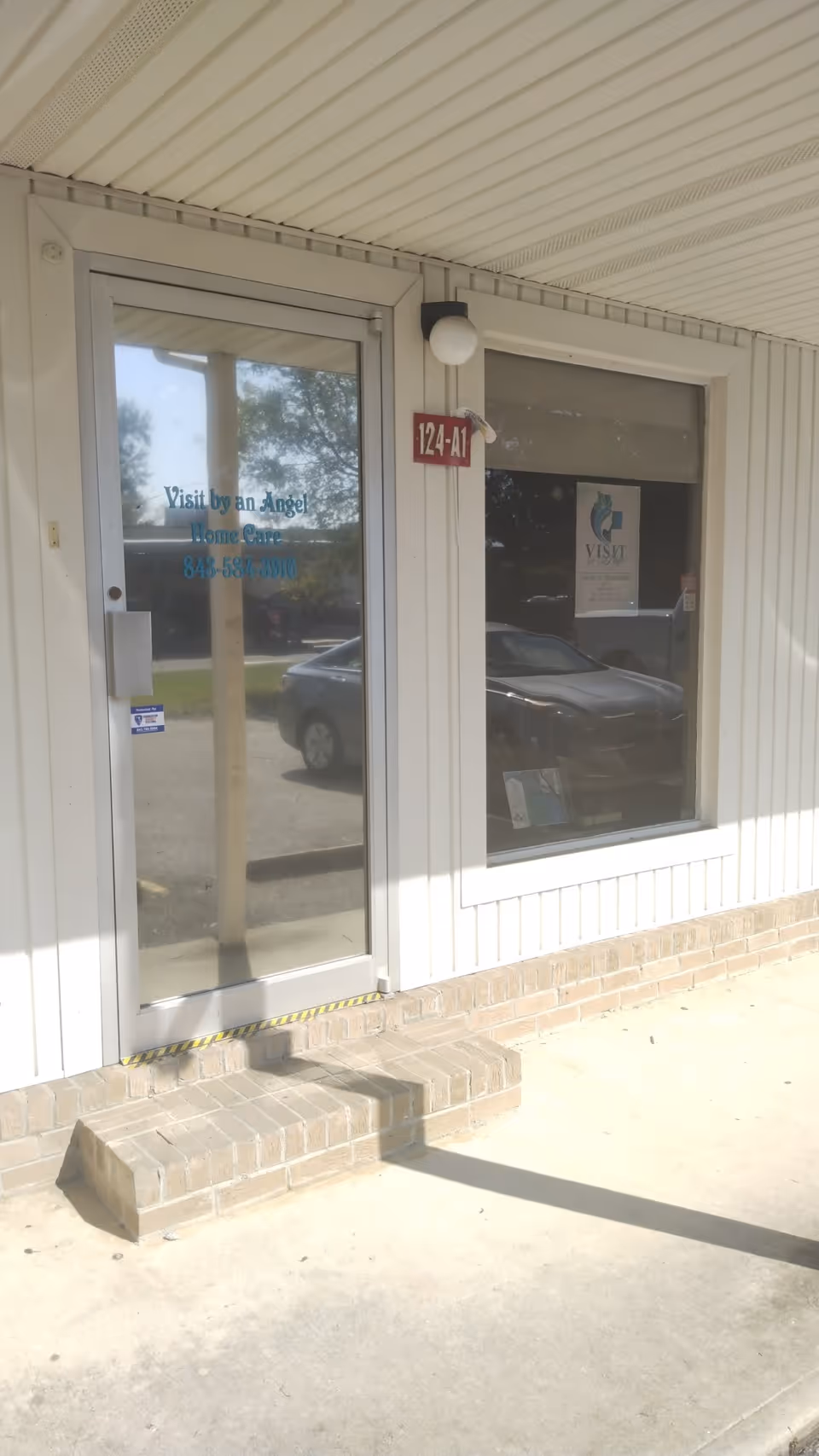 Exterior view of Visit By An Angel Home Care entrance with glass door and steps.