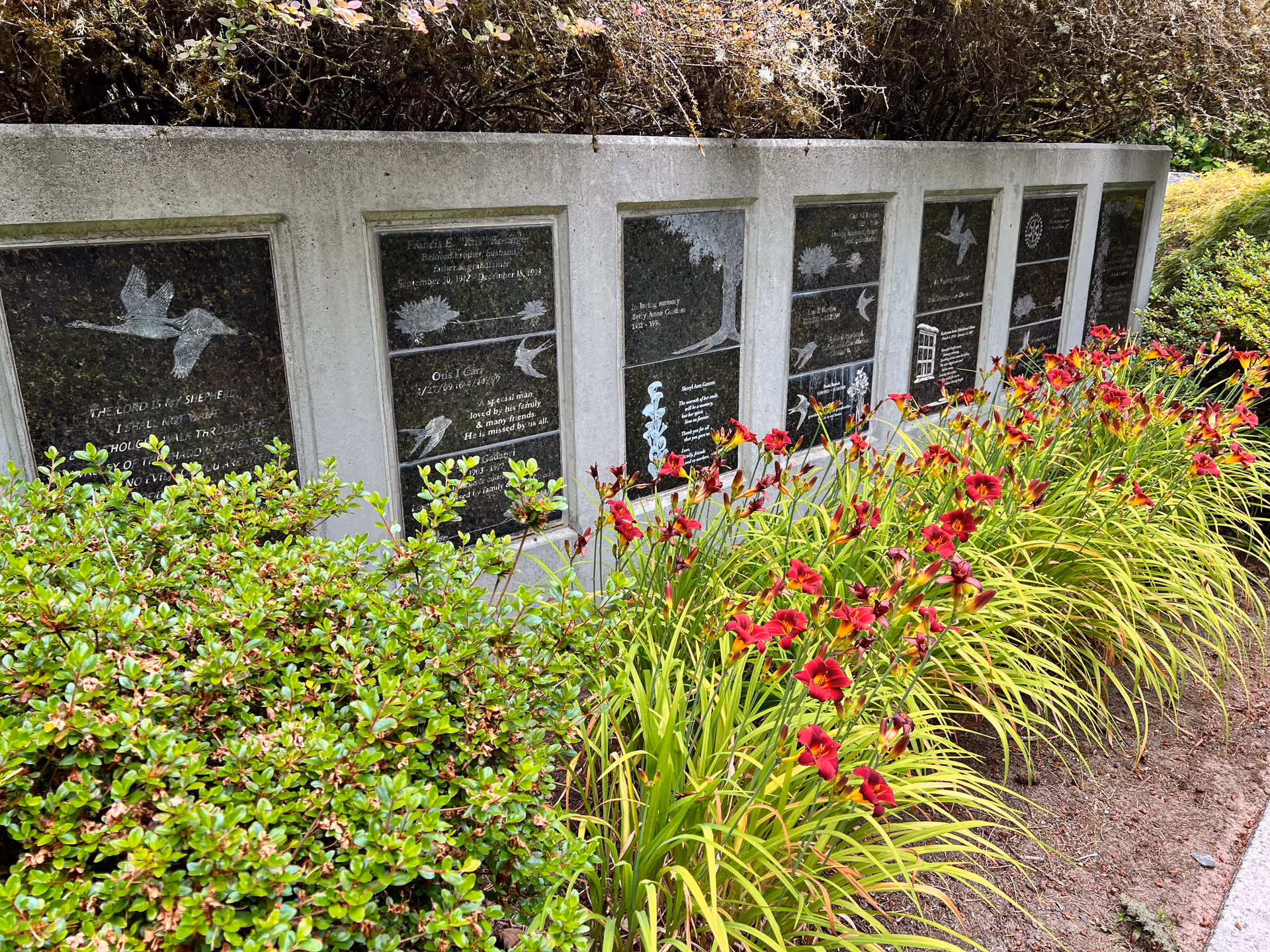 Exterior memorial wall at EvergreenHealth Hospice Services with engraved plaques and lilies.