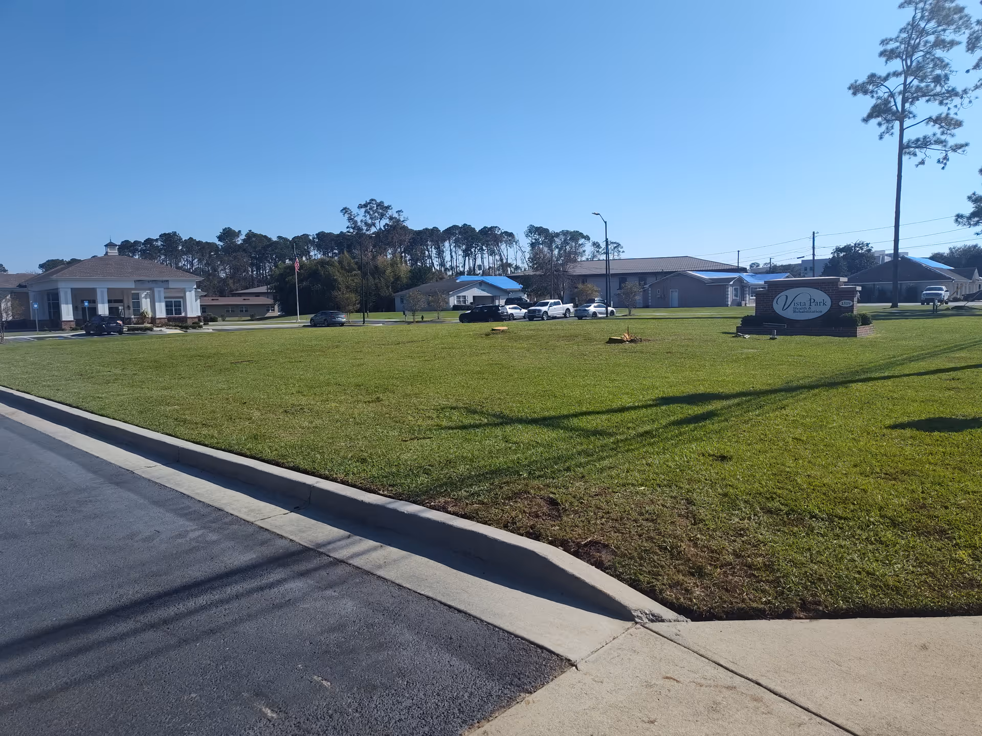Exterior view of Vista Park Health and Rehabilitation with a sign, lawn, and parked cars.