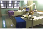 Two patient beds in a hospital-like interior with medical equipment and purple blankets.