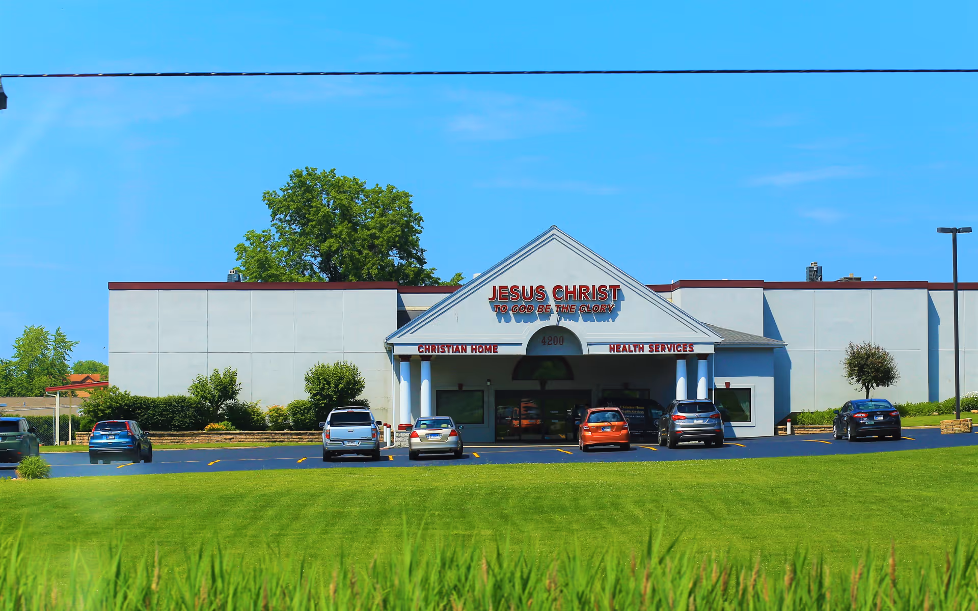 Exterior view of a Christian Home Health Care facility with a parking lot and cars.