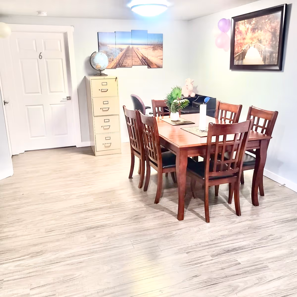 A wooden dining table with six chairs in a bright, cozy dining room.