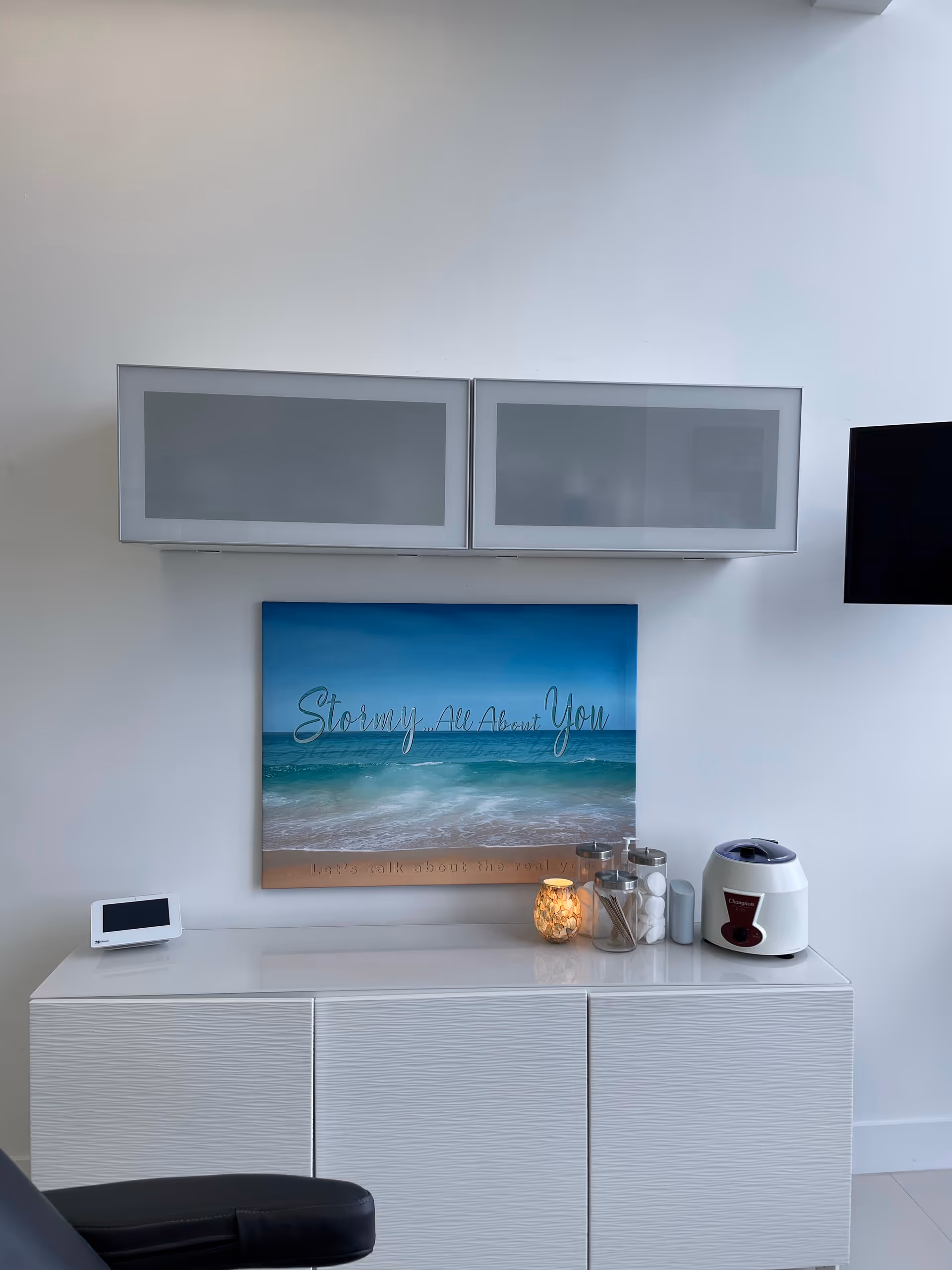 Interior lounge area with white cabinets, seaside artwork, and small appliances.