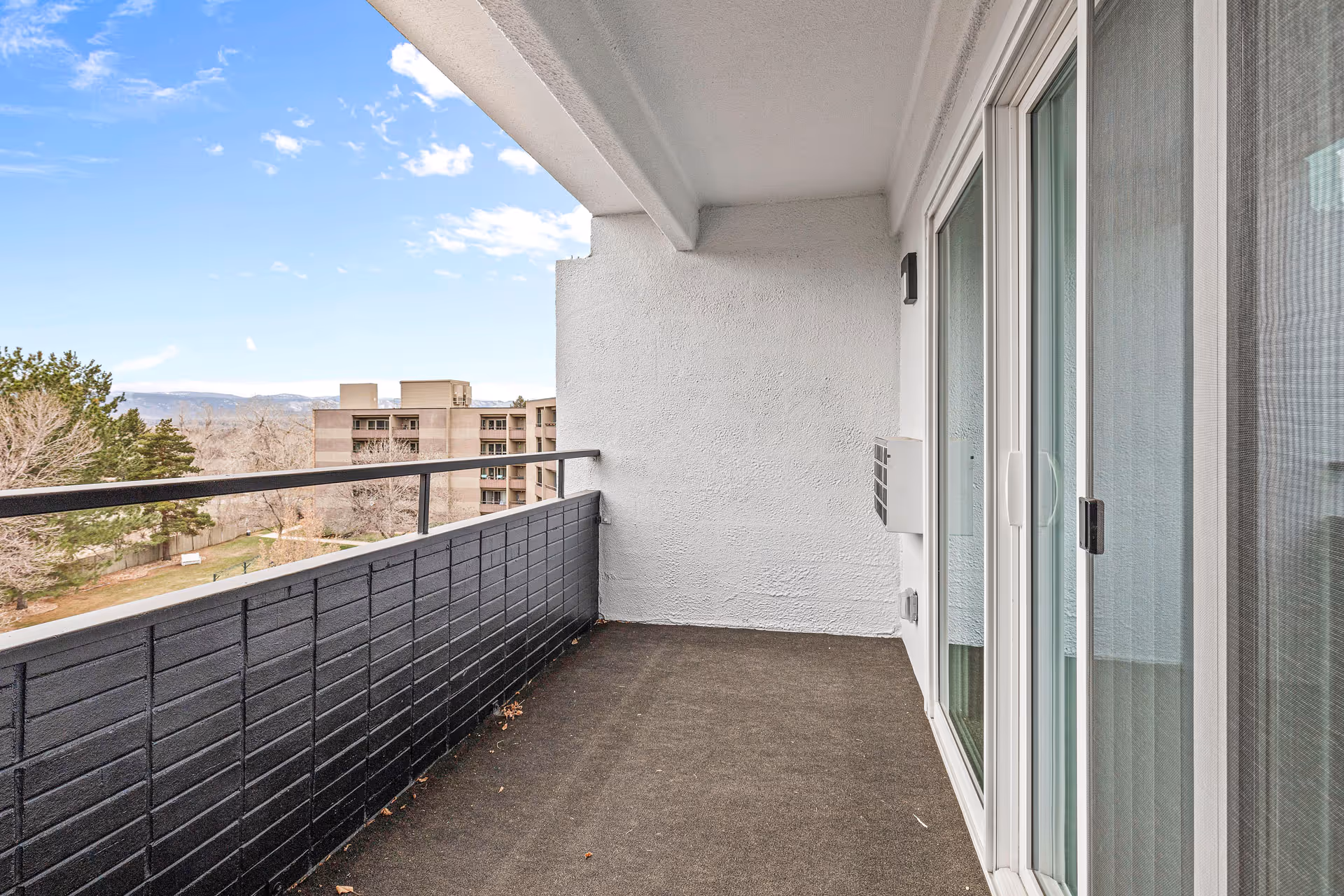 An empty Windemere balcony with sliding doors and a railing.